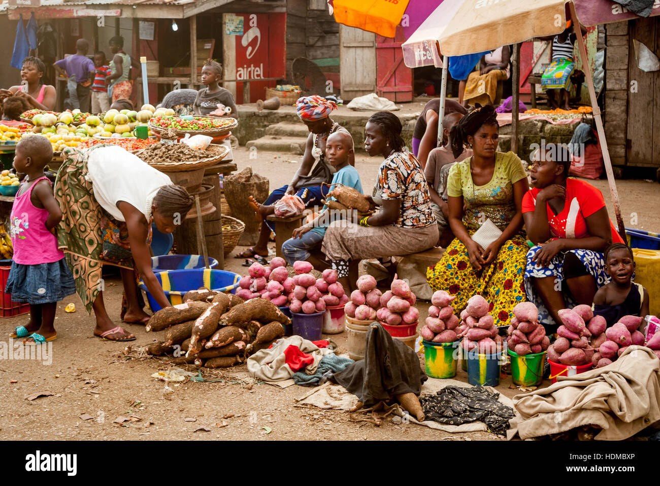 Des racines de manioc et des tubercules ronds et roses sont en vente sur un marché de légumes à Mile 91 ; des vendeuses sont assises parmi des seaux pleins de produits. Mile 91, district de Tonkolili, province du Nord, Sierra Leone Banque D'Images