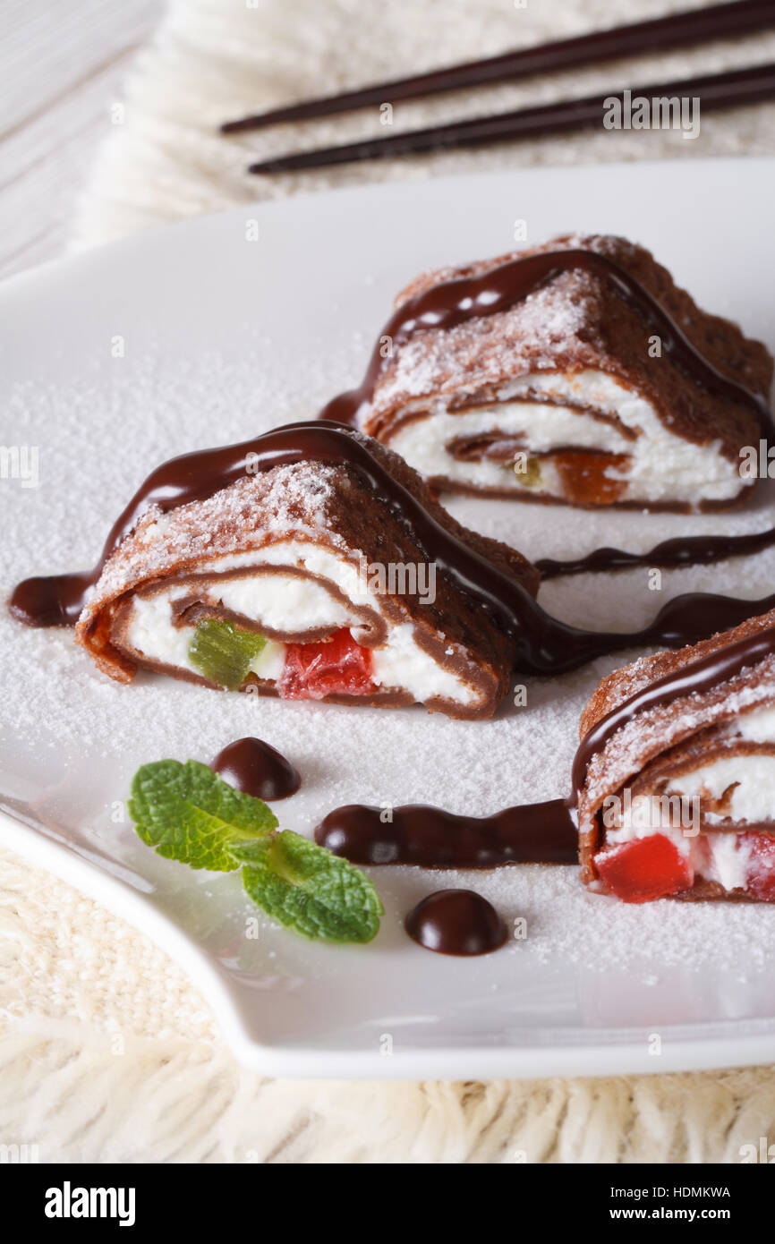 Crêpes au chocolat japonais rouleau avec du fromage et des fruits sur une plaque verticale close-up. Banque D'Images