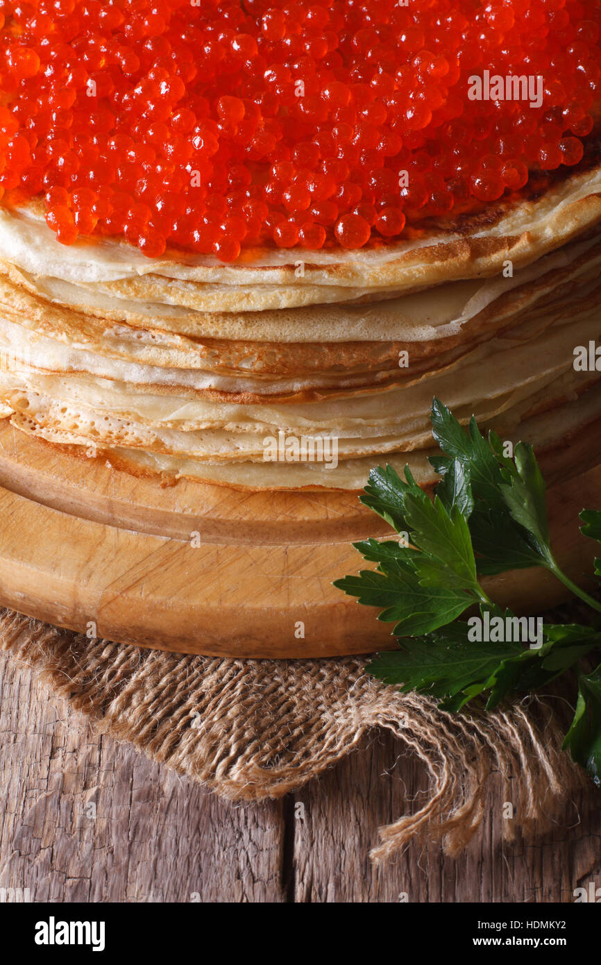 Une pile de crêpes minces avec du caviar rouge close-up vertical, style rustique. Banque D'Images