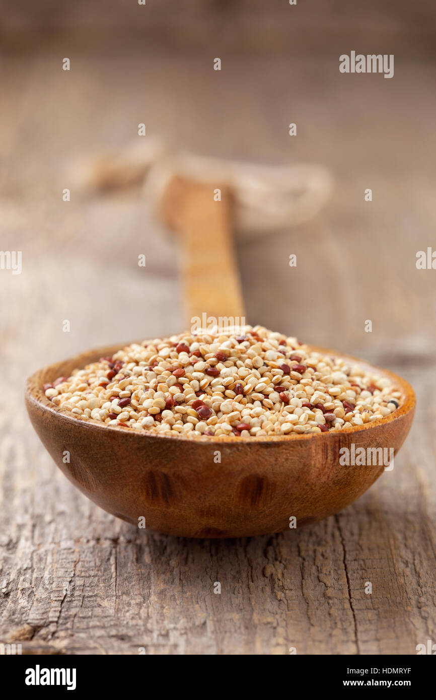 Le quinoa dans une cuillère en bois sur l'ancien fond de bois Banque D'Images