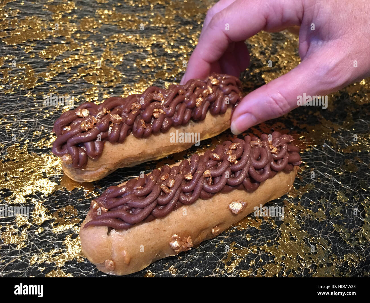 Une femme ayant atteint pour un eclair au chocolat belge, Close up Banque D'Images