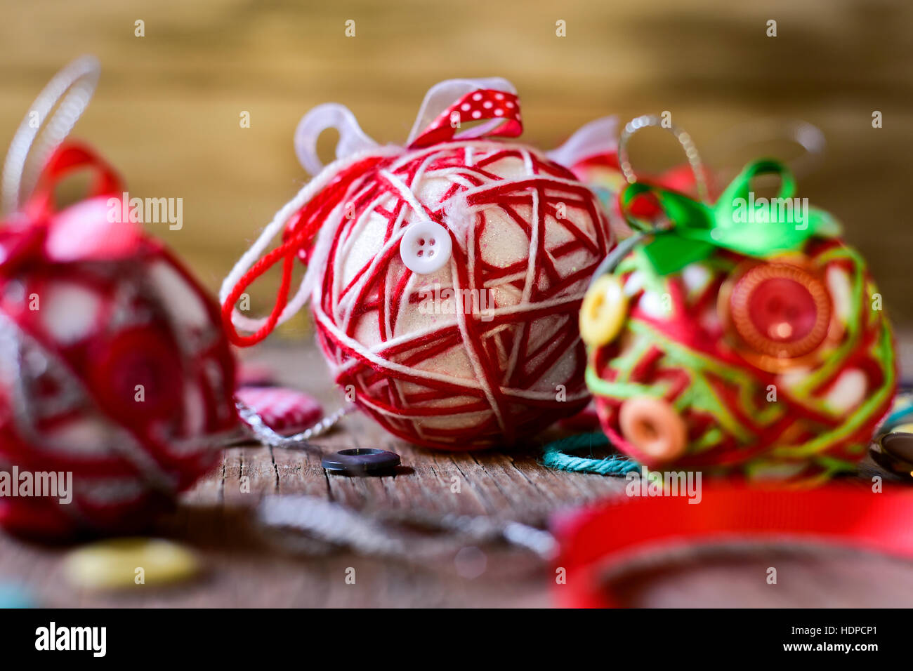 Libre de quelques boules de noël faites à la main, fait avec ribbon bow, cordes et boutons de couleurs différentes, sur une surface en bois rustique Banque D'Images