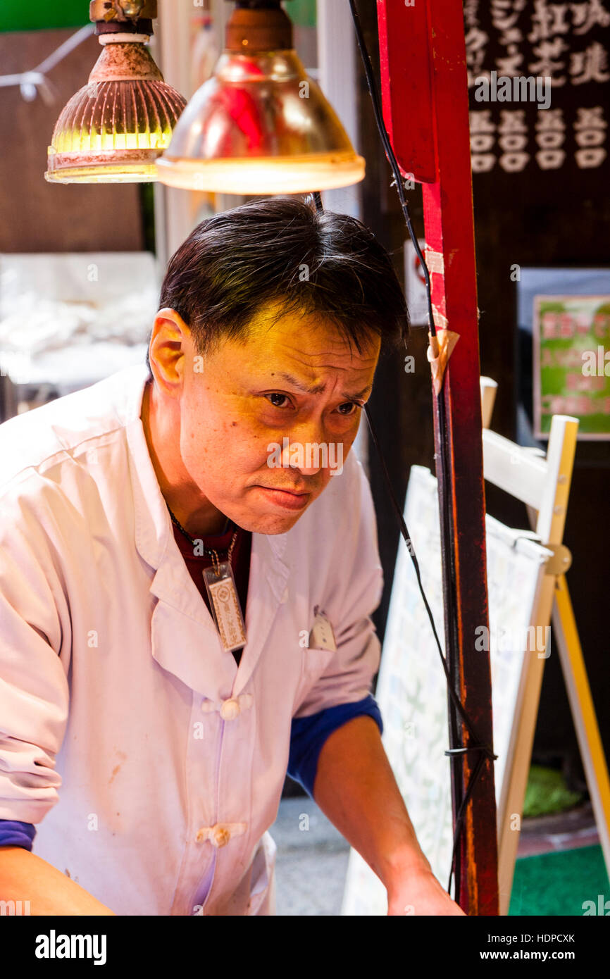 Le Japon, Kobe Nankinmachi, Chinatown. Sweet Potato Chinese takeaway food en plein air. Cook's visage alors qu'il prend la moitié de l'alimentation de l'expression de colère. Banque D'Images