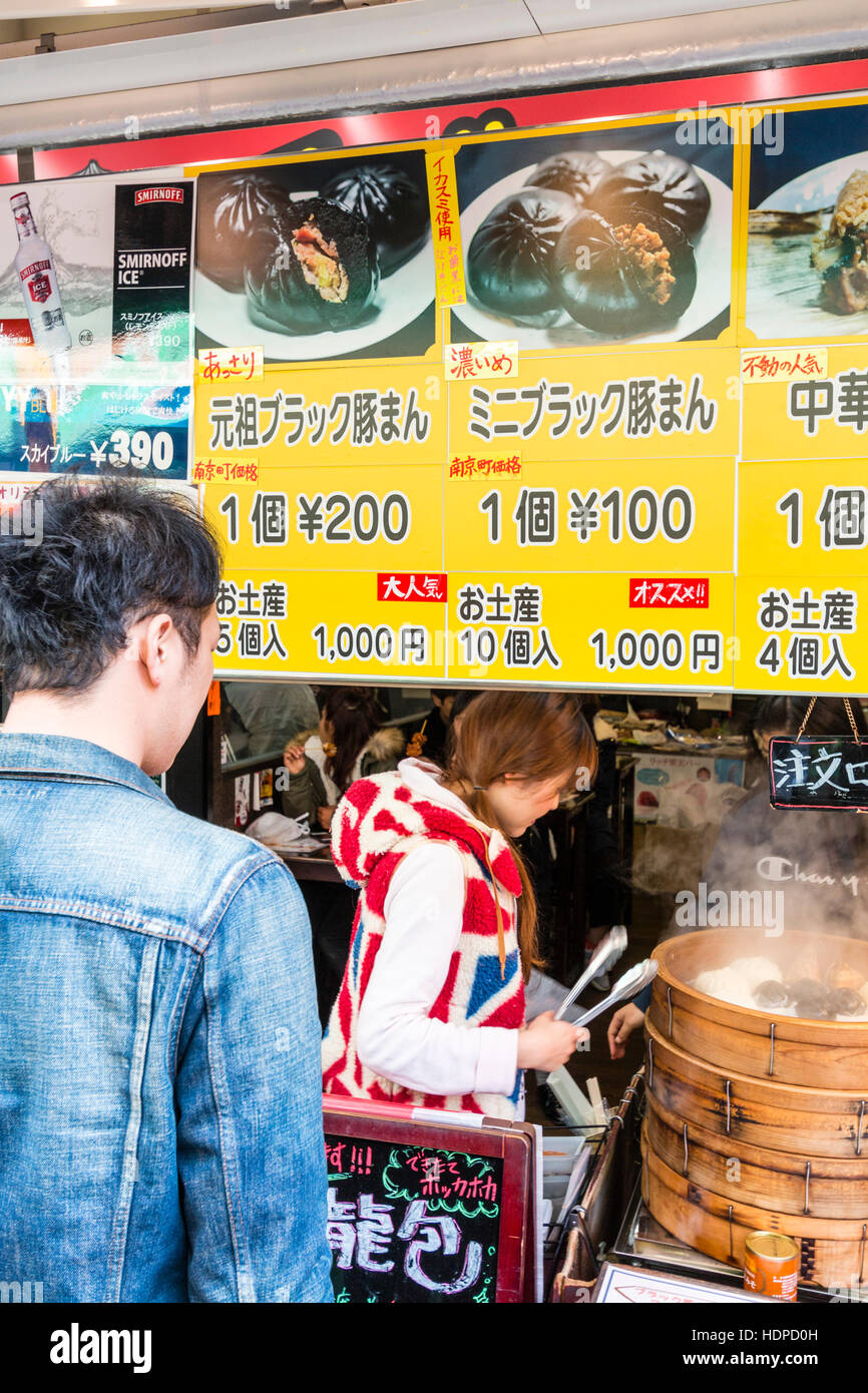 Le Japon, Kobe Nankinmachi, Chinatown. L'homme japonais d'acheter du Chinois dim sum avec blocage de port du vendeur Union Jack dessus. Le bol de dim-sum. Banque D'Images
