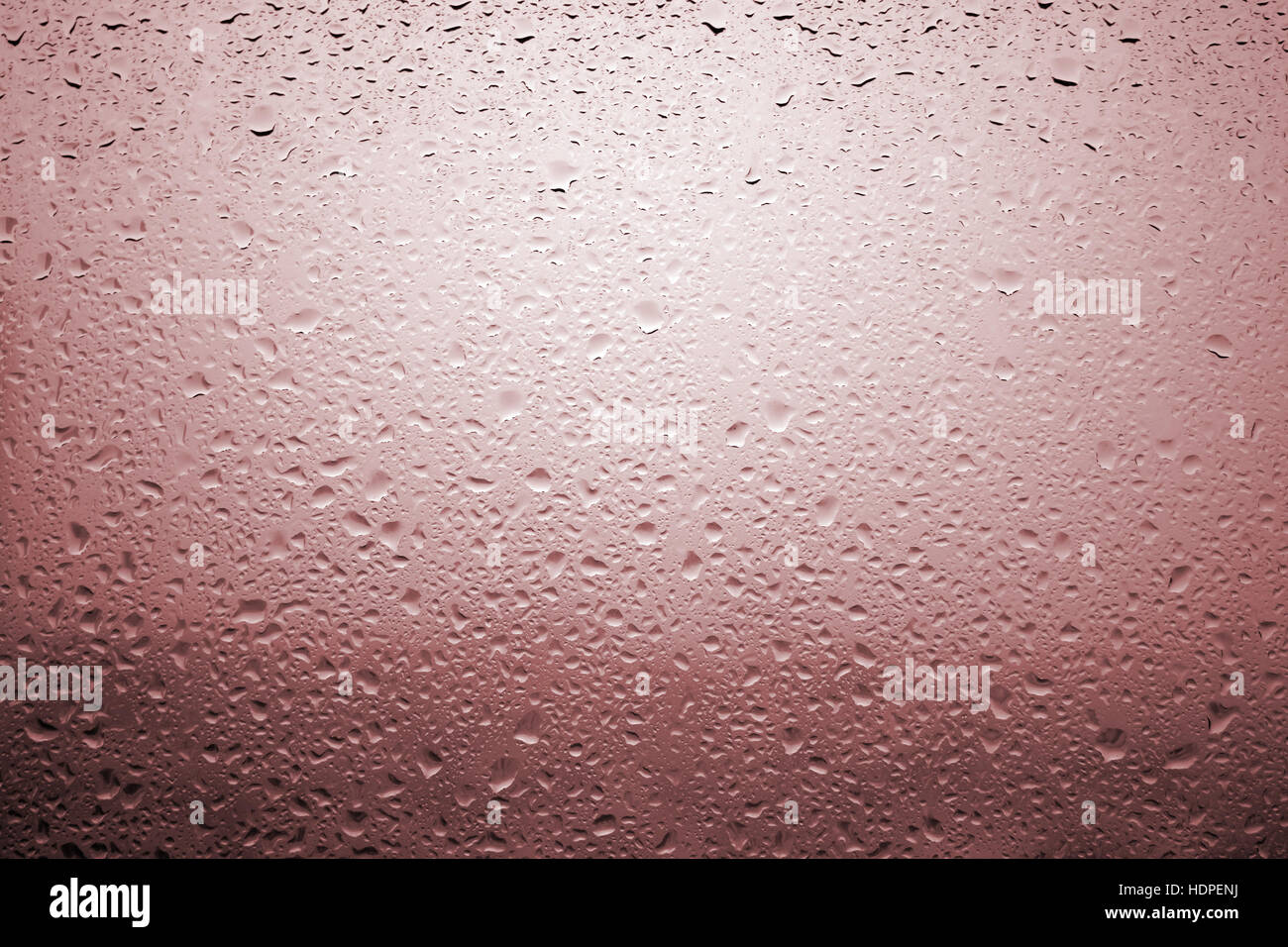 Gouttes de pluie sur une vitre de fenêtre avec paysage très diffuse de couleur orange rougeâtre Banque D'Images