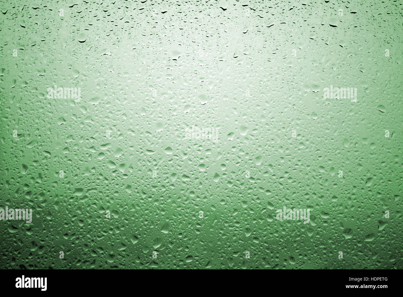 Gouttes de pluie sur une vitre de fenêtre avec paysage très diffuse de couleur vert pâle Banque D'Images