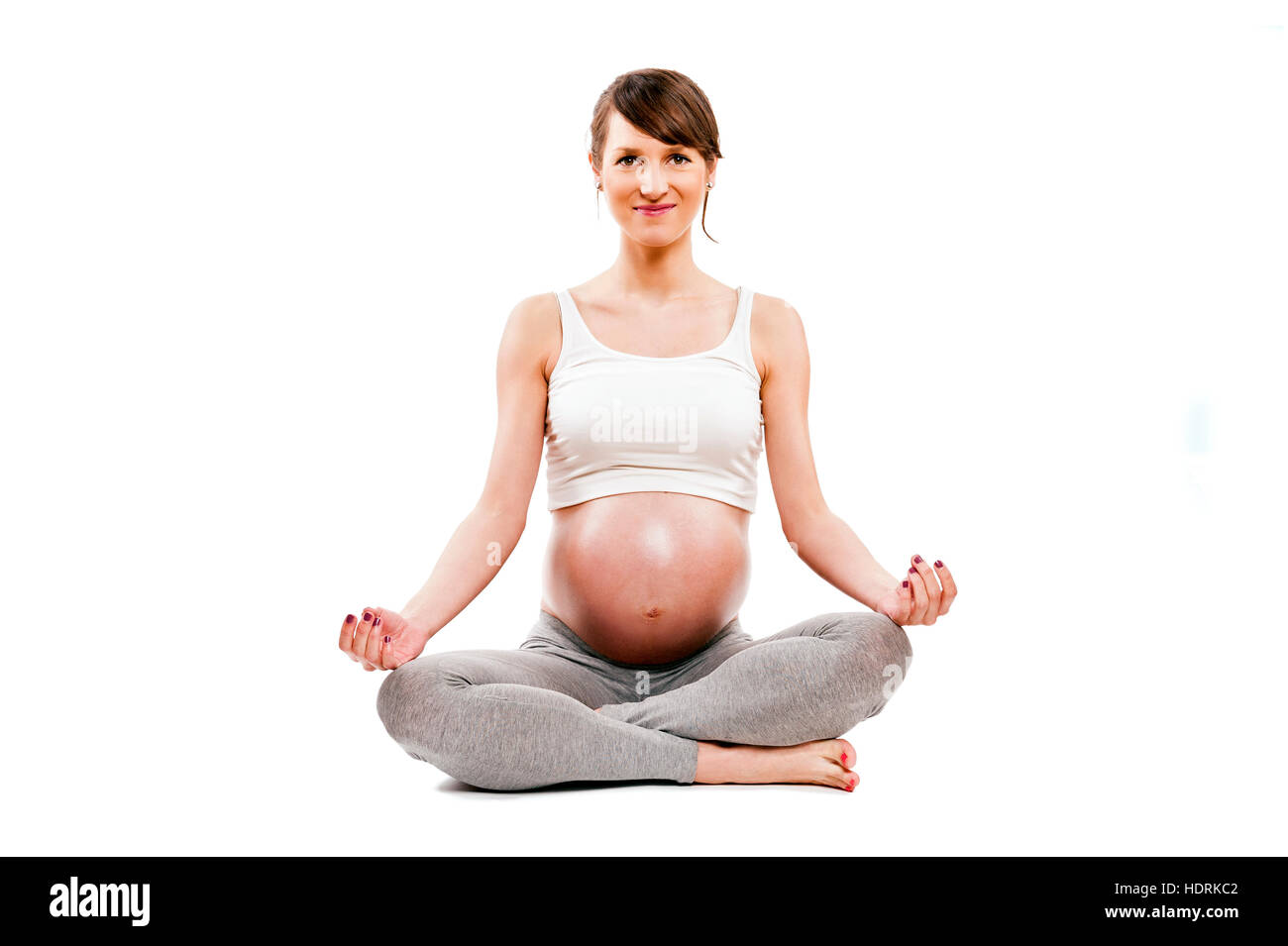 Méditant sur la maternité. Close-up of pregnant woman meditating while sitting in lotus position Banque D'Images