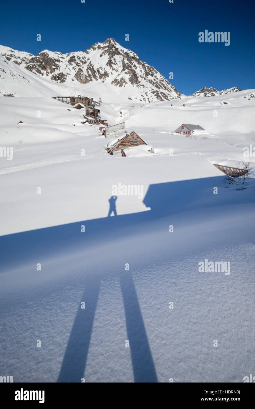 Le photographe Doug Lindstrand prend Une photo de son ombre à Hatcher Pass, près de la mine Independence à la fin de l'hiver.L'ancienne mine délabrée... Banque D'Images