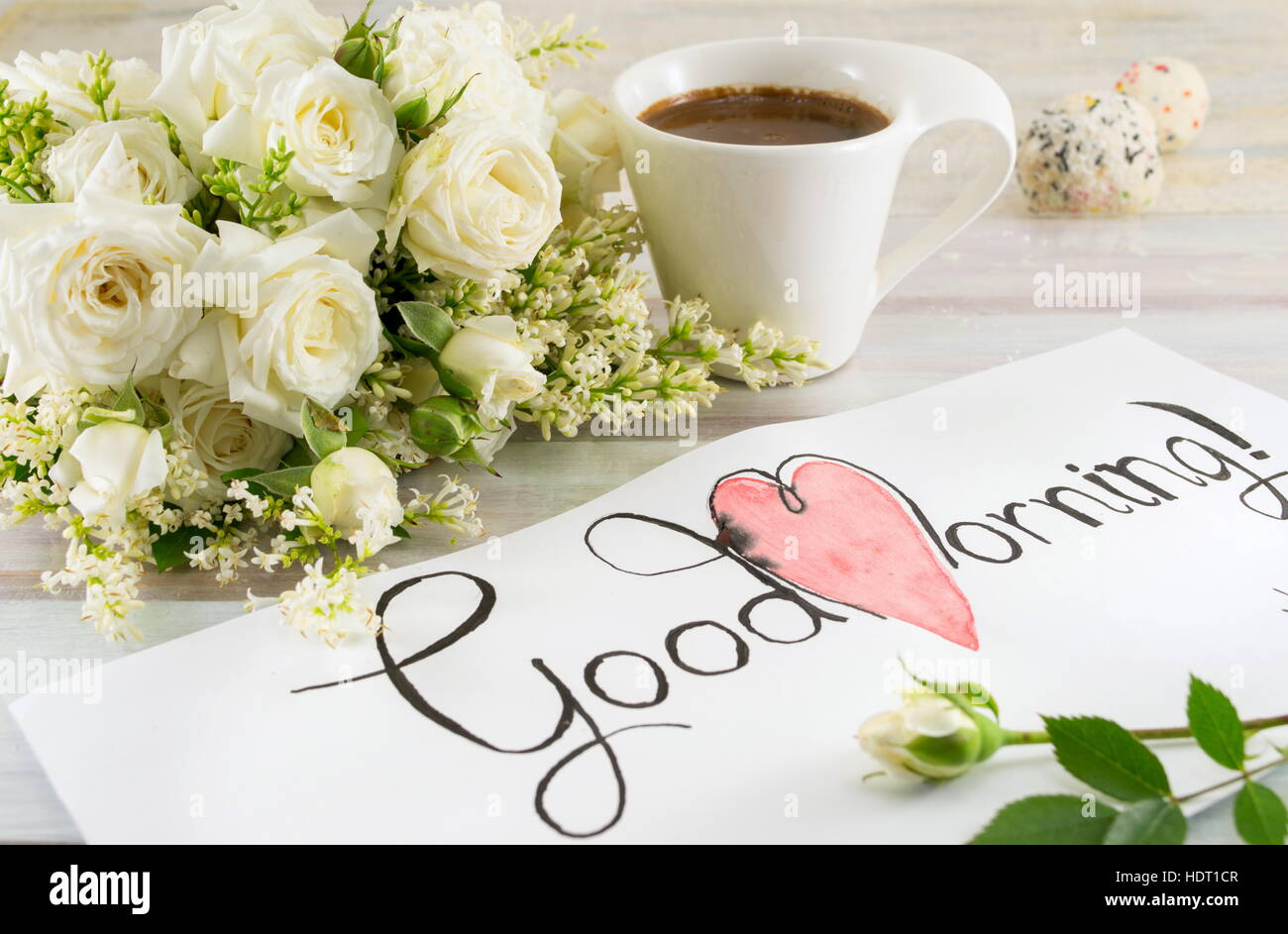 Des roses blanches, du café et du bon matin note sur une table Banque D'Images