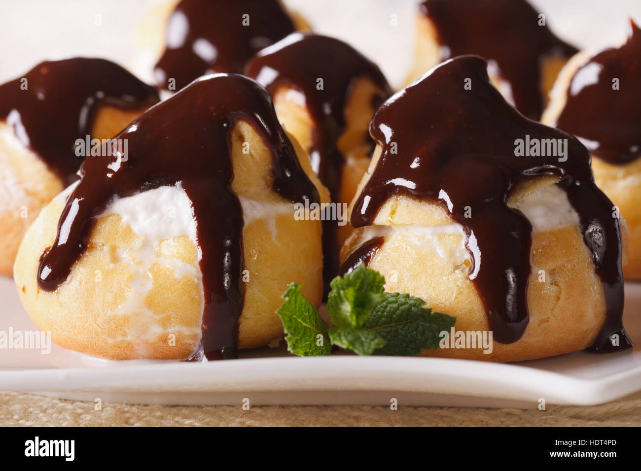 Les profiteroles au chocolat et à la crème glaçage sur une plaque horizontale de macro. Banque D'Images