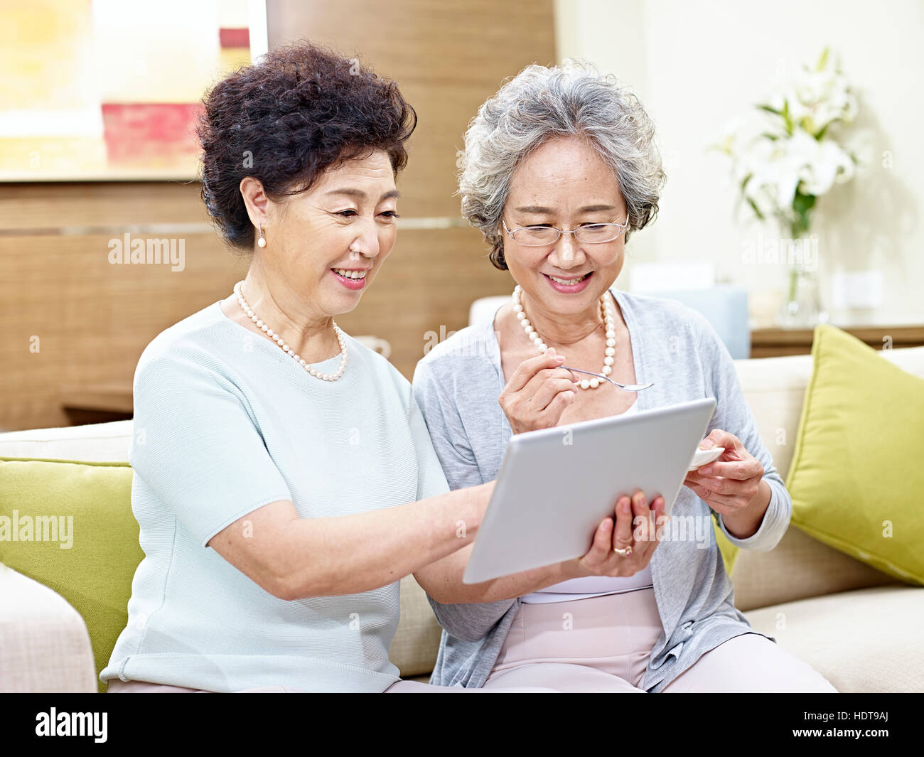 Deux hauts femmes asiatiques assis sur la table à l'aide d'ordinateur tablette, heureux et souriant Banque D'Images