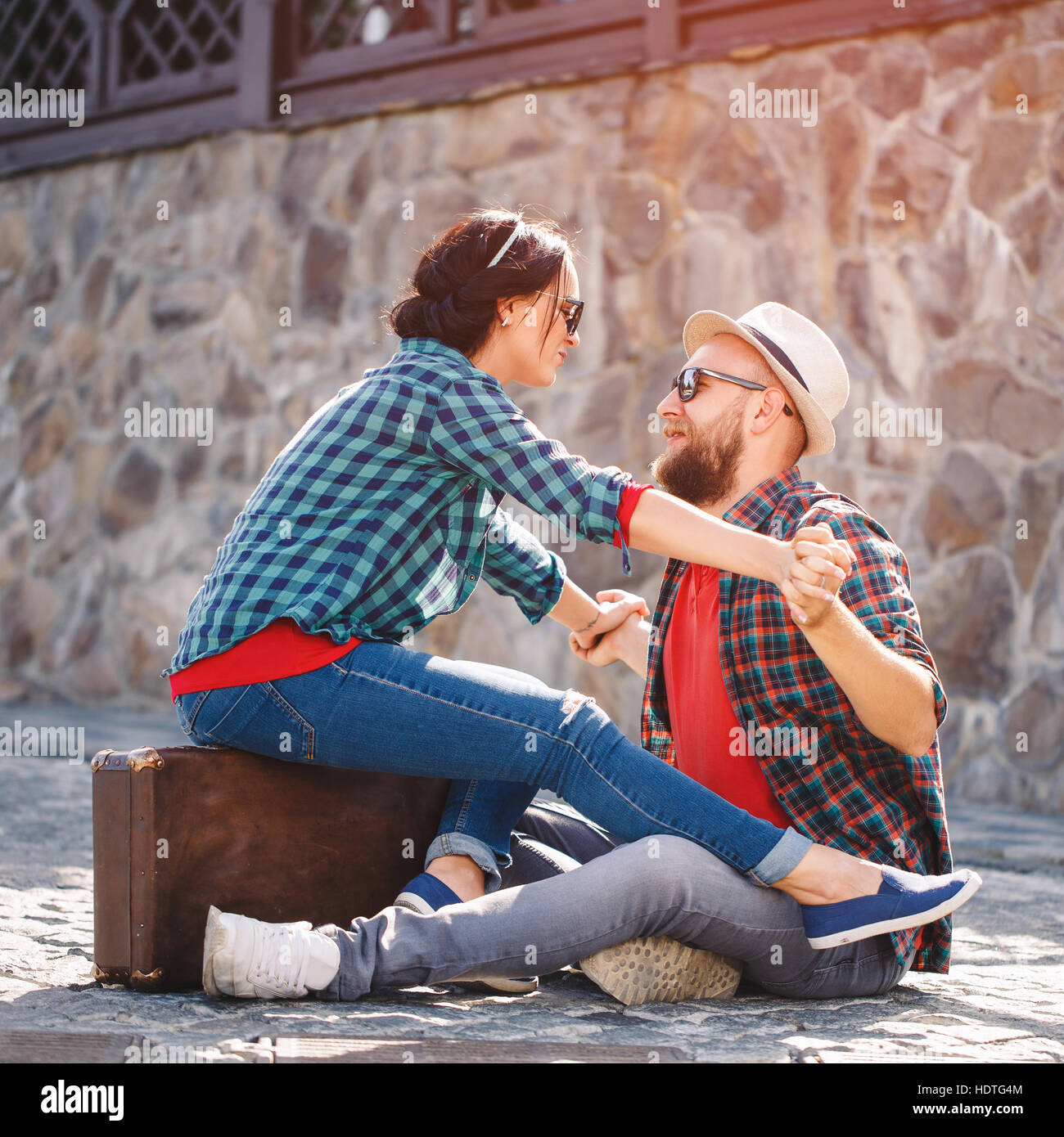 Couple amoureux assis sur route avec suitcase Banque D'Images