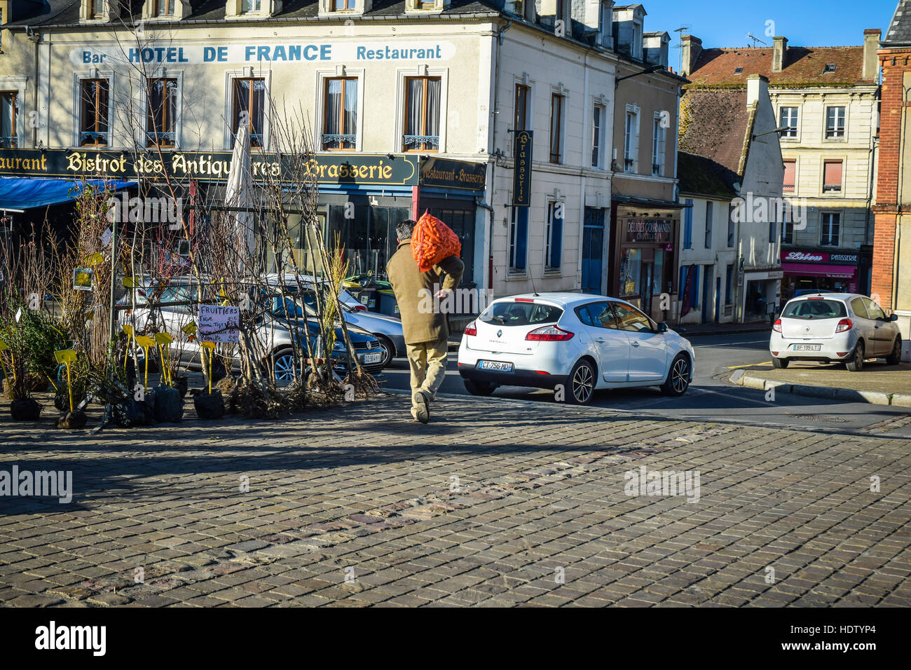 L'homme énorme sac toting de carottes au marché hebdomadaire régional à Saint-Pierre-sur-Dives, Calvados, Normandie, France. Banque D'Images