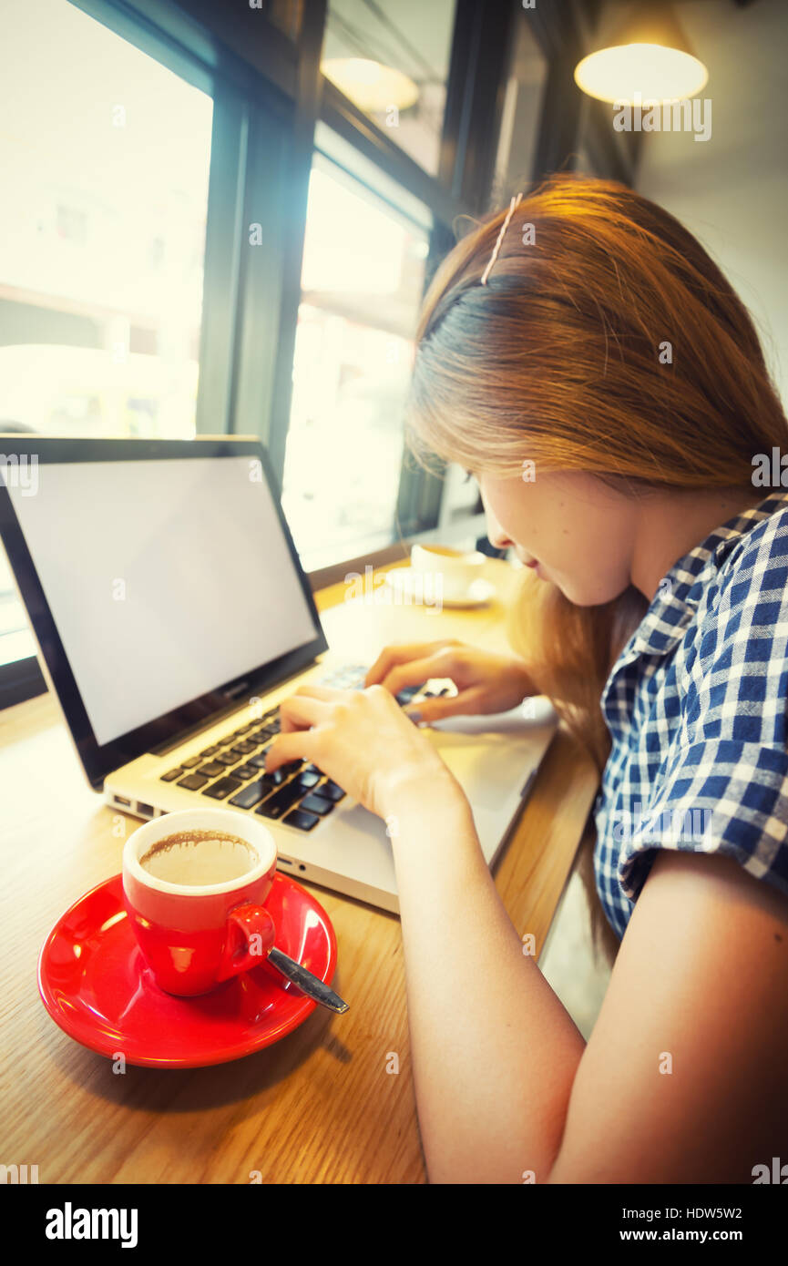 Femme à l'aide d'un ordinateur portable pendant une pause-café, les vacances concept, effet vintage Banque D'Images
