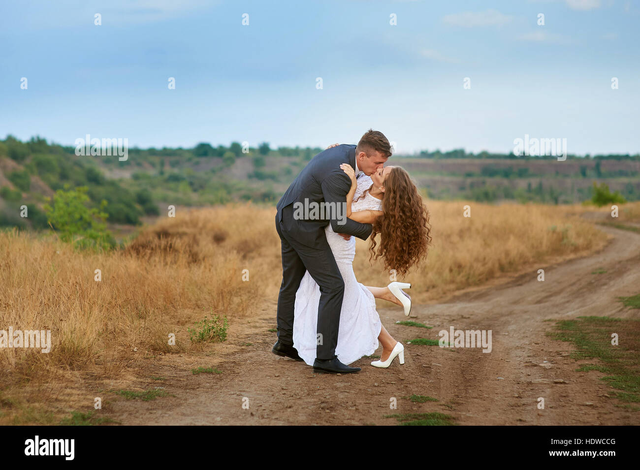 Heureux époux marcher dans un champ de jour de mariage Banque D'Images Heureux époux marcher dans un champ de jour de mariage Banque D'Images