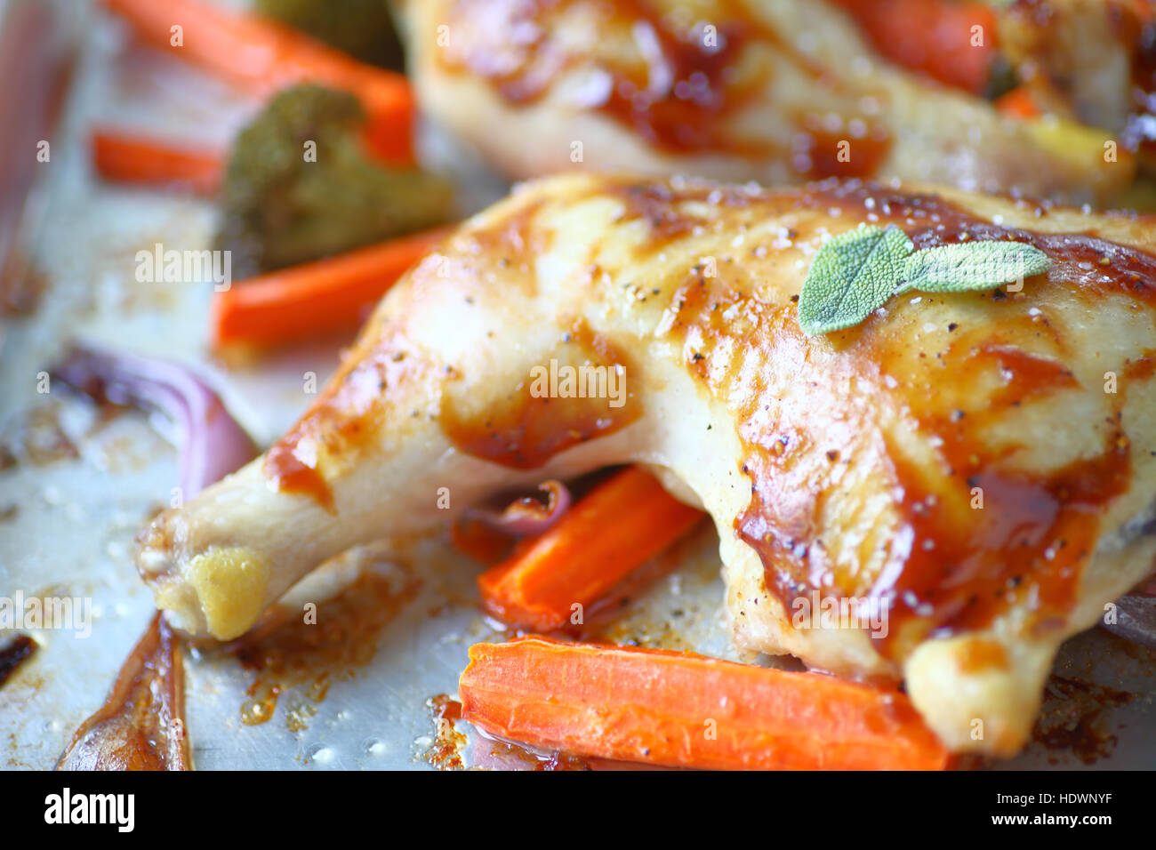 Poulet rôti avec des feuilles de sauge fraîches, carottes, brocoli et les oignons sur un pan de feuille Banque D'Images