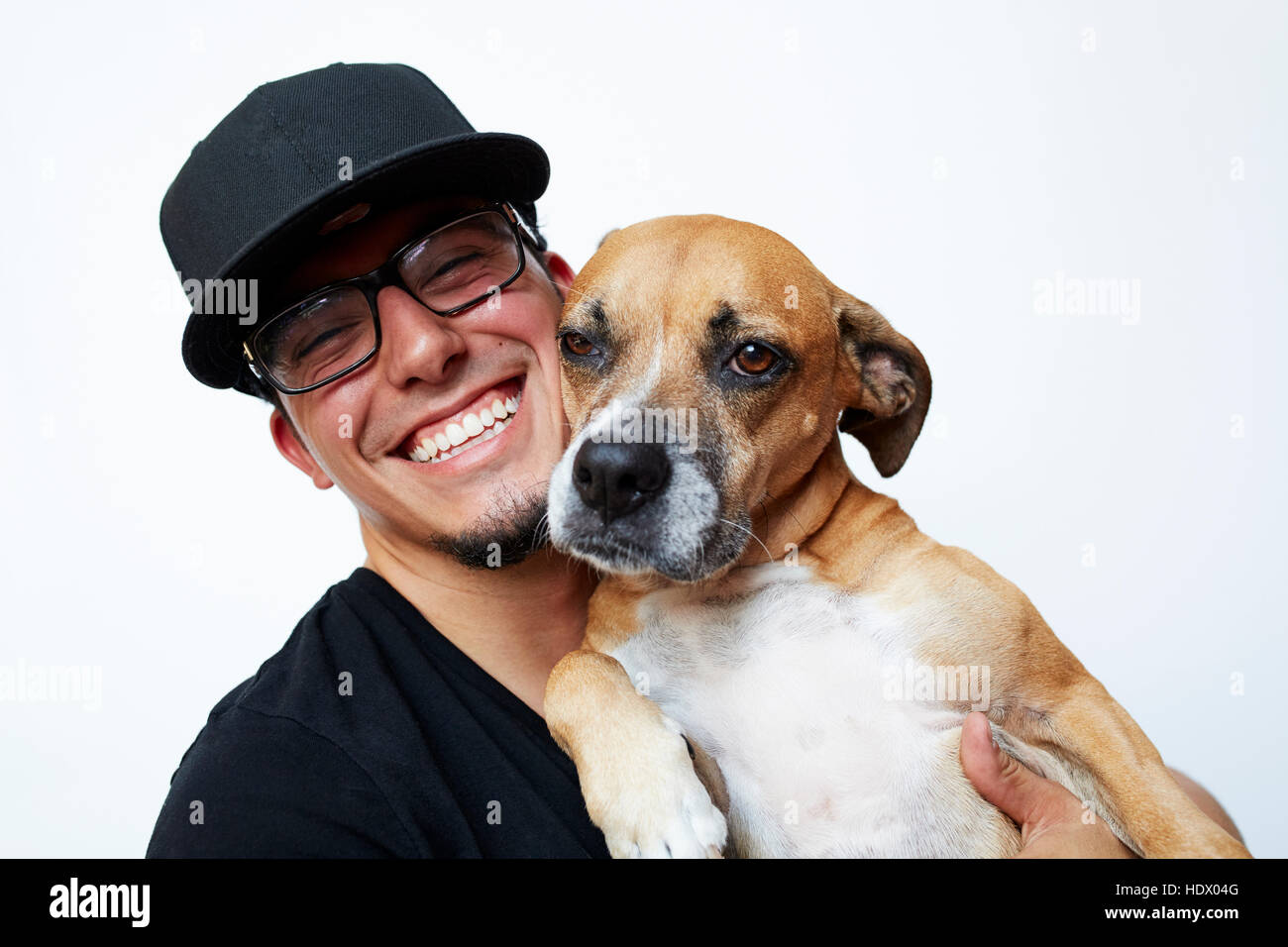 Smiling Hispanic man hugging dog Banque D'Images