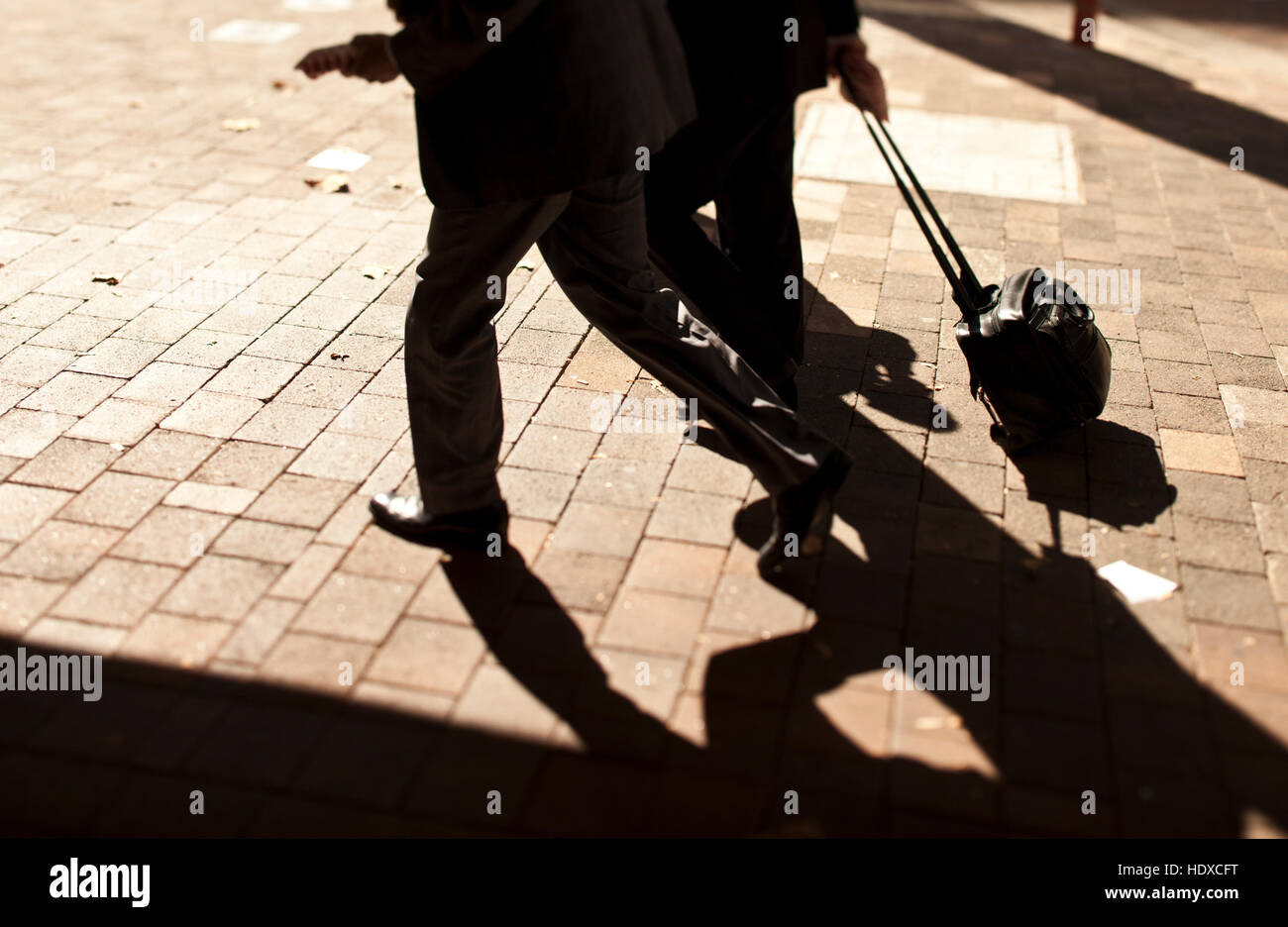 Silhouette d'hommes d'affaires avec des mallettes de matériel roulant sur la brique sentier Banque D'Images