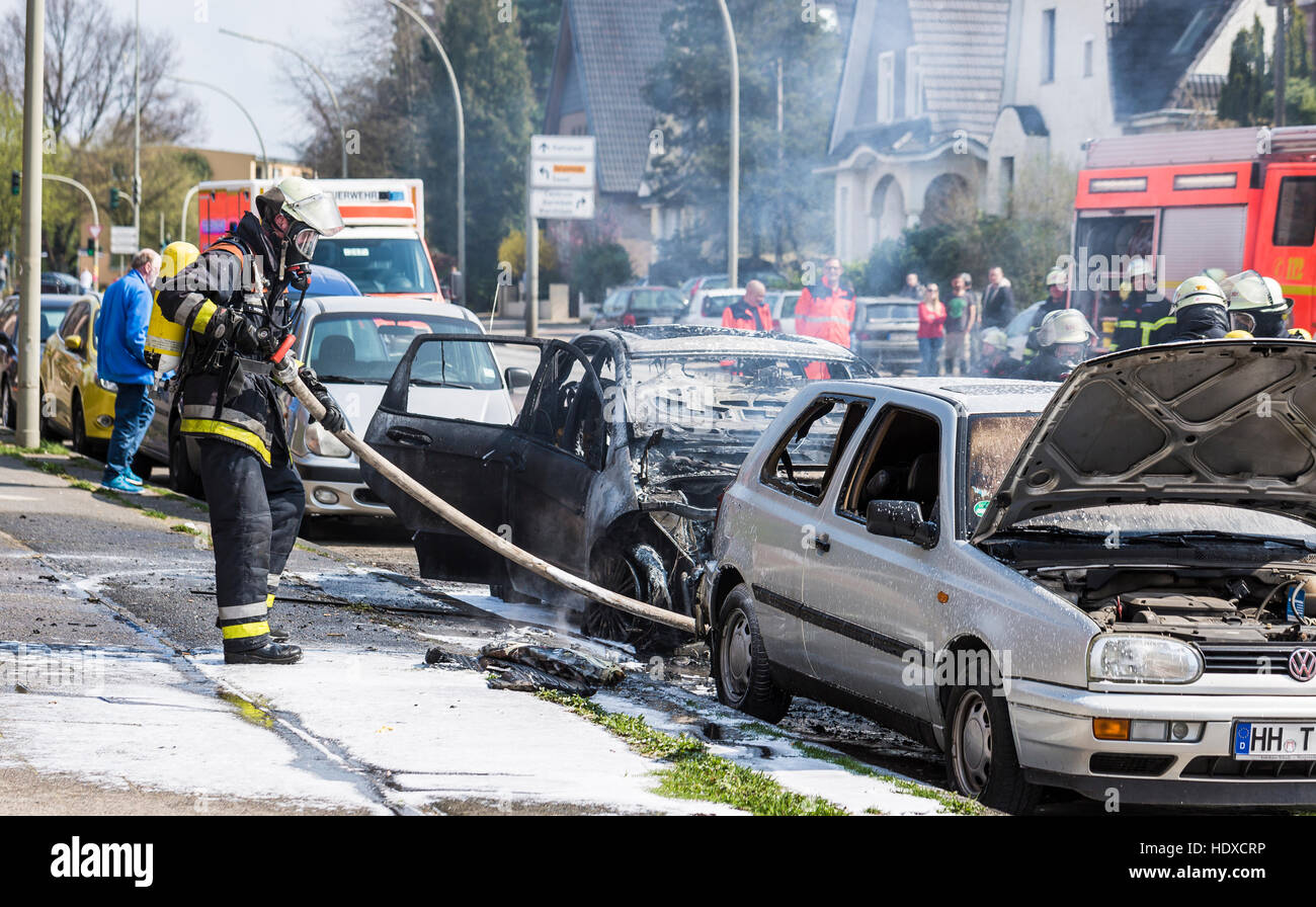 Pompiers éteindre voiture en flammes Banque D'Images