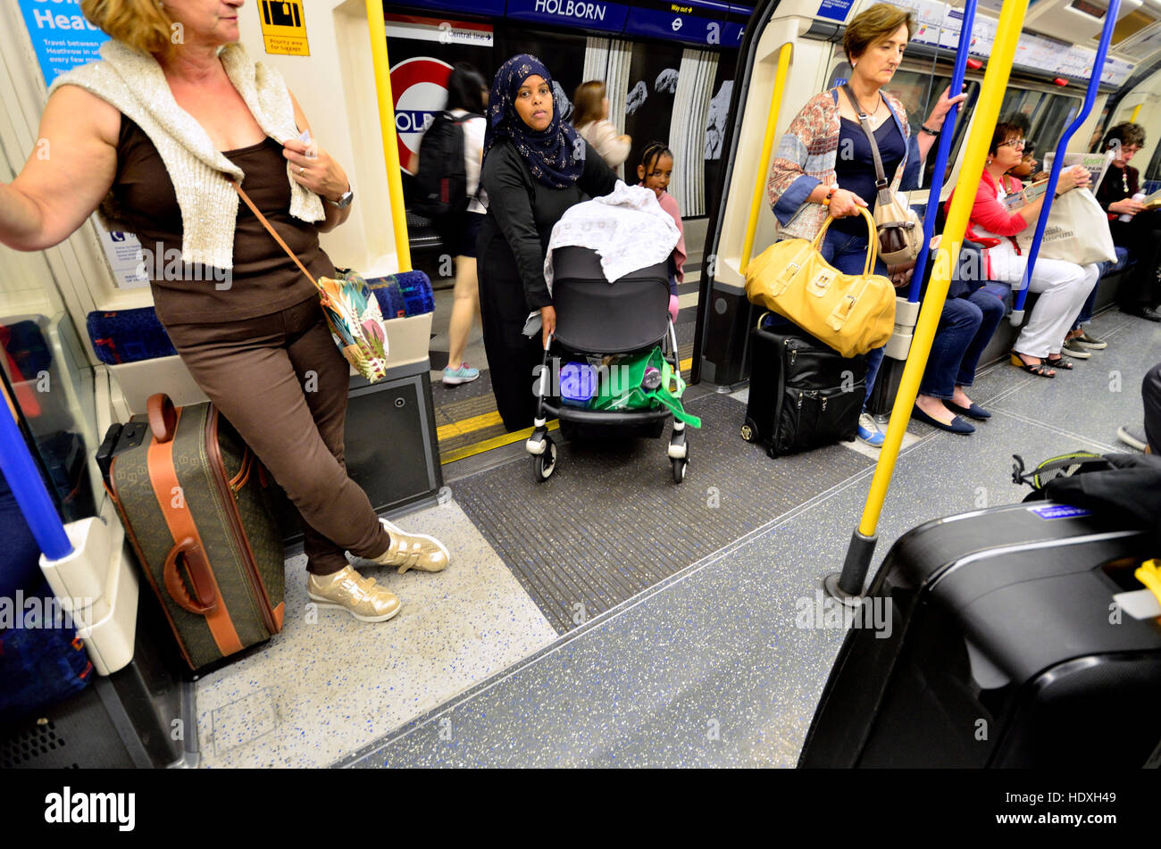 Londres, Angleterre, Royaume-Uni. Femme musulmane de monter dans un train de tube avec un landau et un enfant Banque D'Images