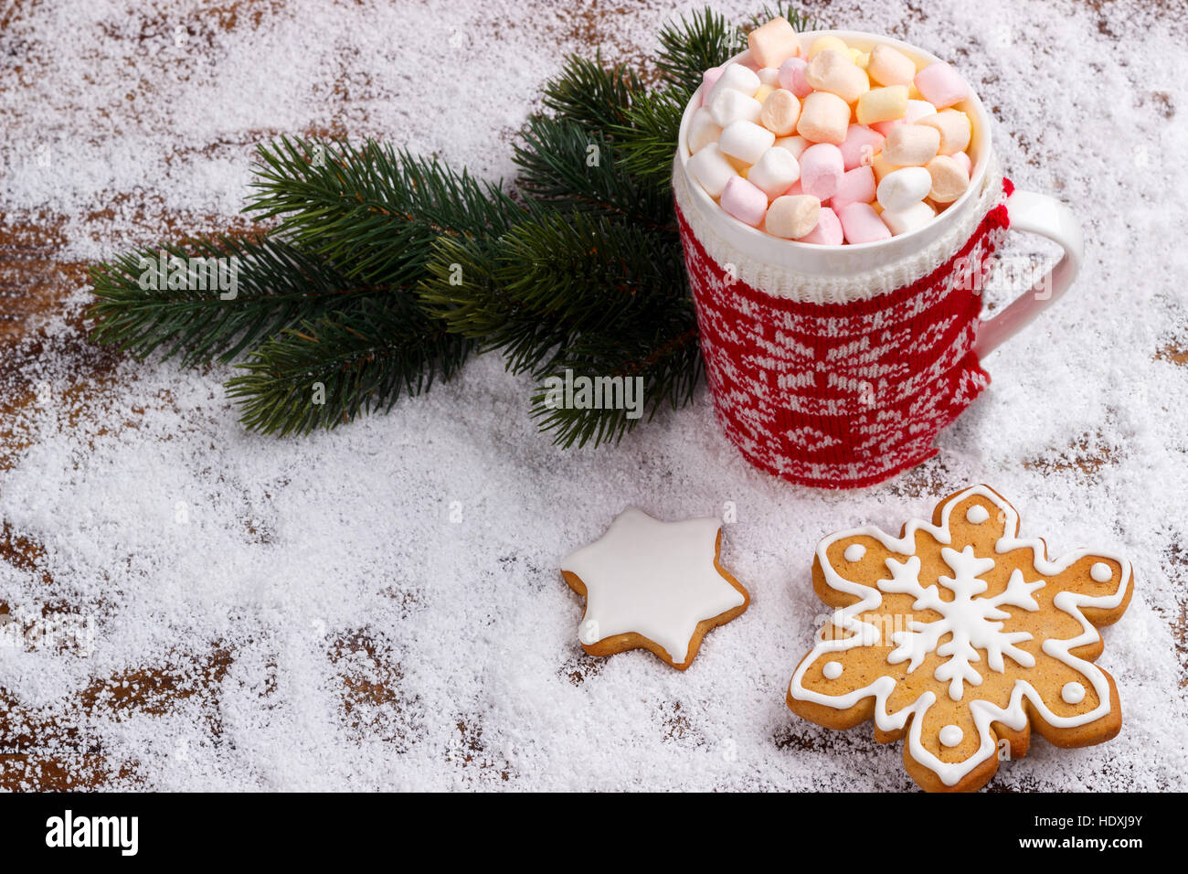 Chocolat chaud avec guimauves fondues en rouge tasse et pain d'épices cookies sur la neige. Vue de dessus avec copie espace Banque D'Images