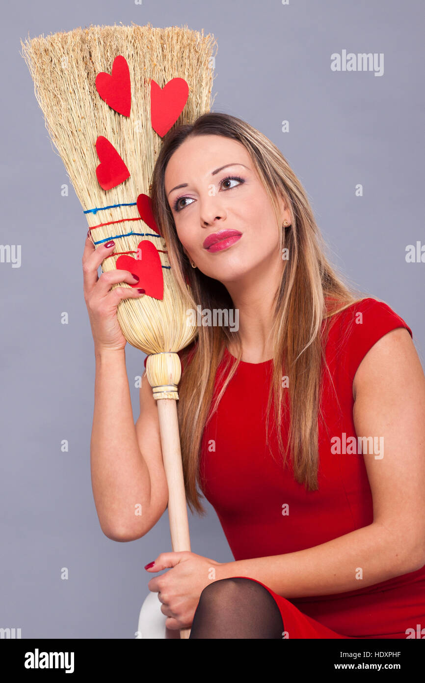 Appartement de vacances St.Valentin, belle femme posant avec coeurs rouges en papier sur le balai Banque D'Images