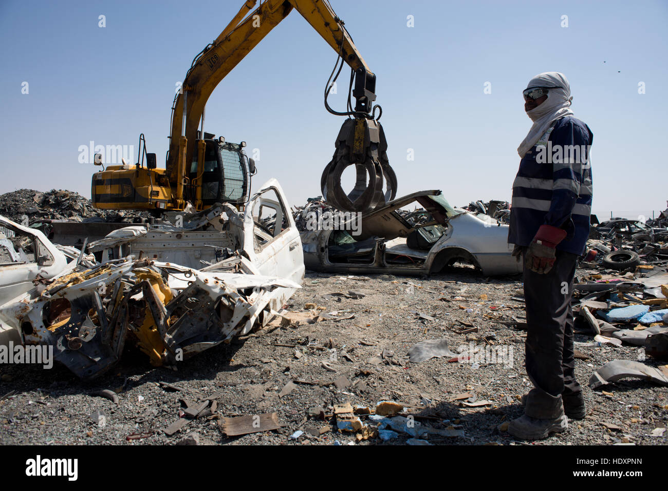 Travailleur migrant observe alors que voiture est écrasé pour recyclage, EAU Banque D'Images