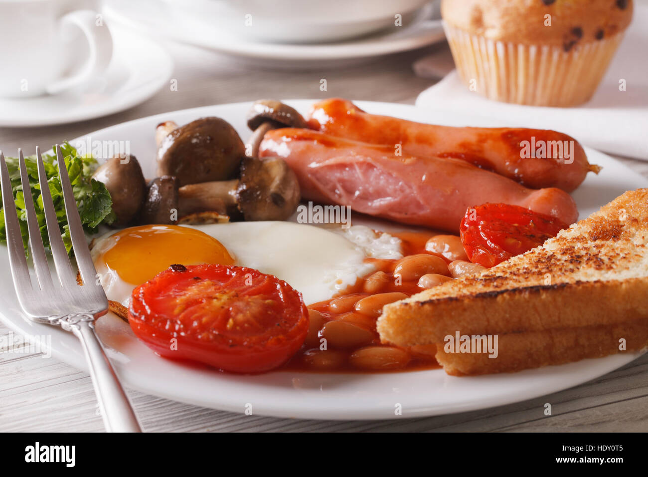 Petit-déjeuner anglais : œufs, saucisses, tomates, haricots et champignons sur une assiette. Banque D'Images