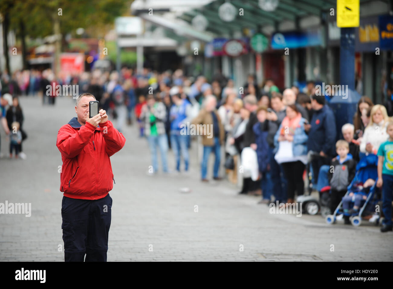 Un homme utilise un téléphone mobile pour prendre des photos dans un centre-ville. Banque D'Images