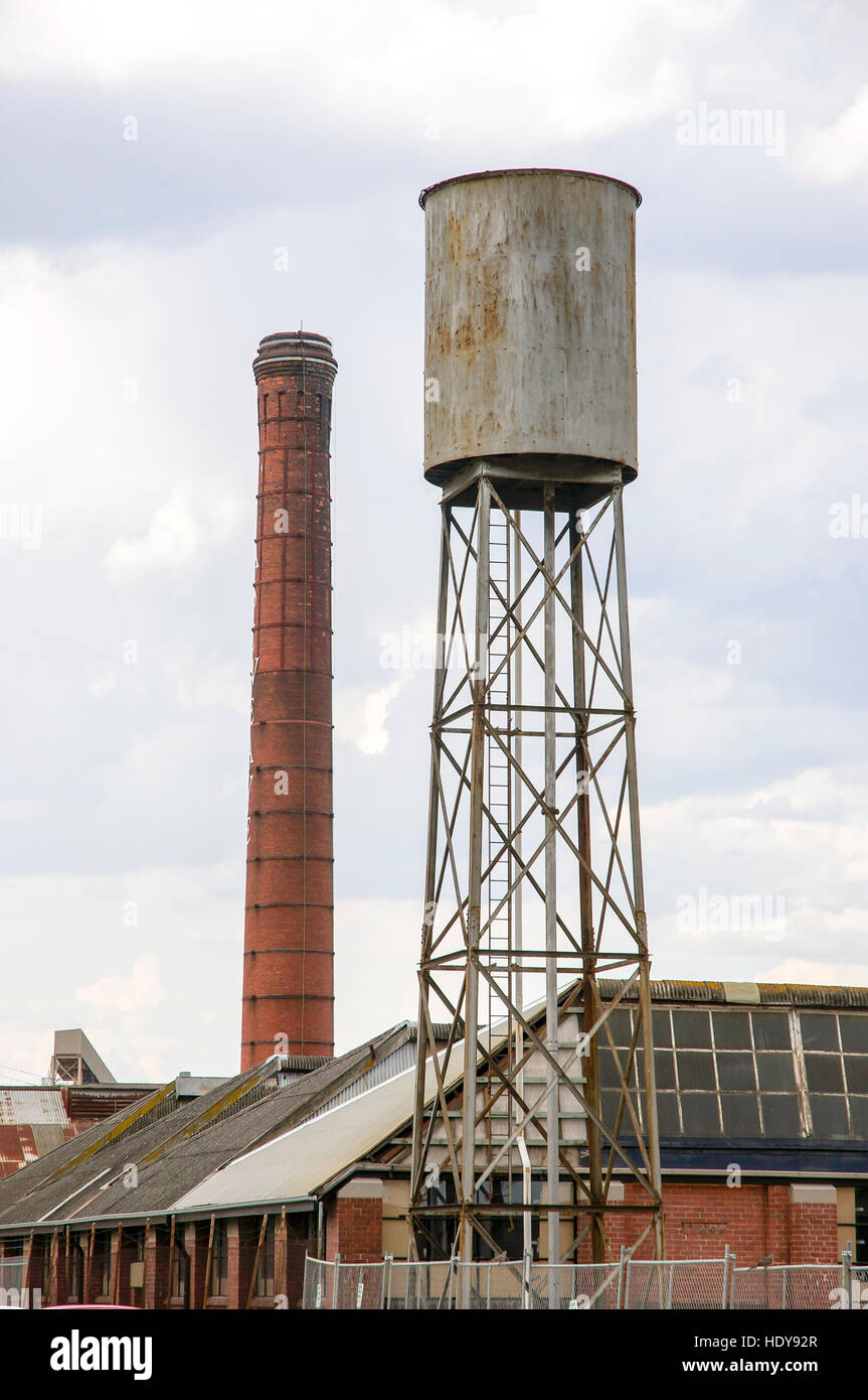 Les structures industrielles abandonnées y compris cheminée en brique et un grand réservoir d'eau surélevé à Geelong, en Australie. Banque D'Images