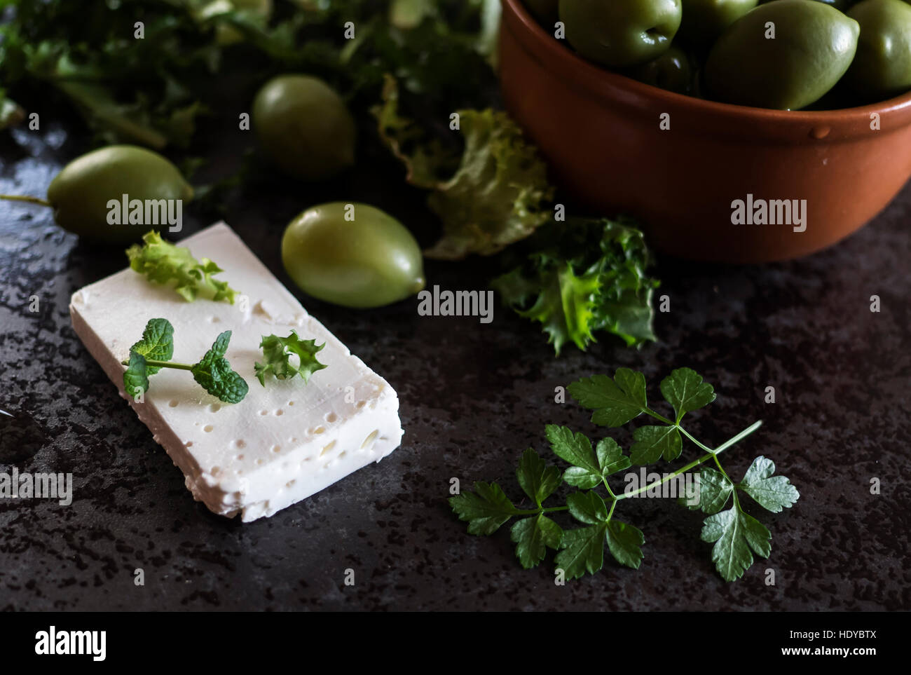 Le fromage Feta aux olives et d'herbes vertes sur fond de marbre gris. Selective focus Banque D'Images