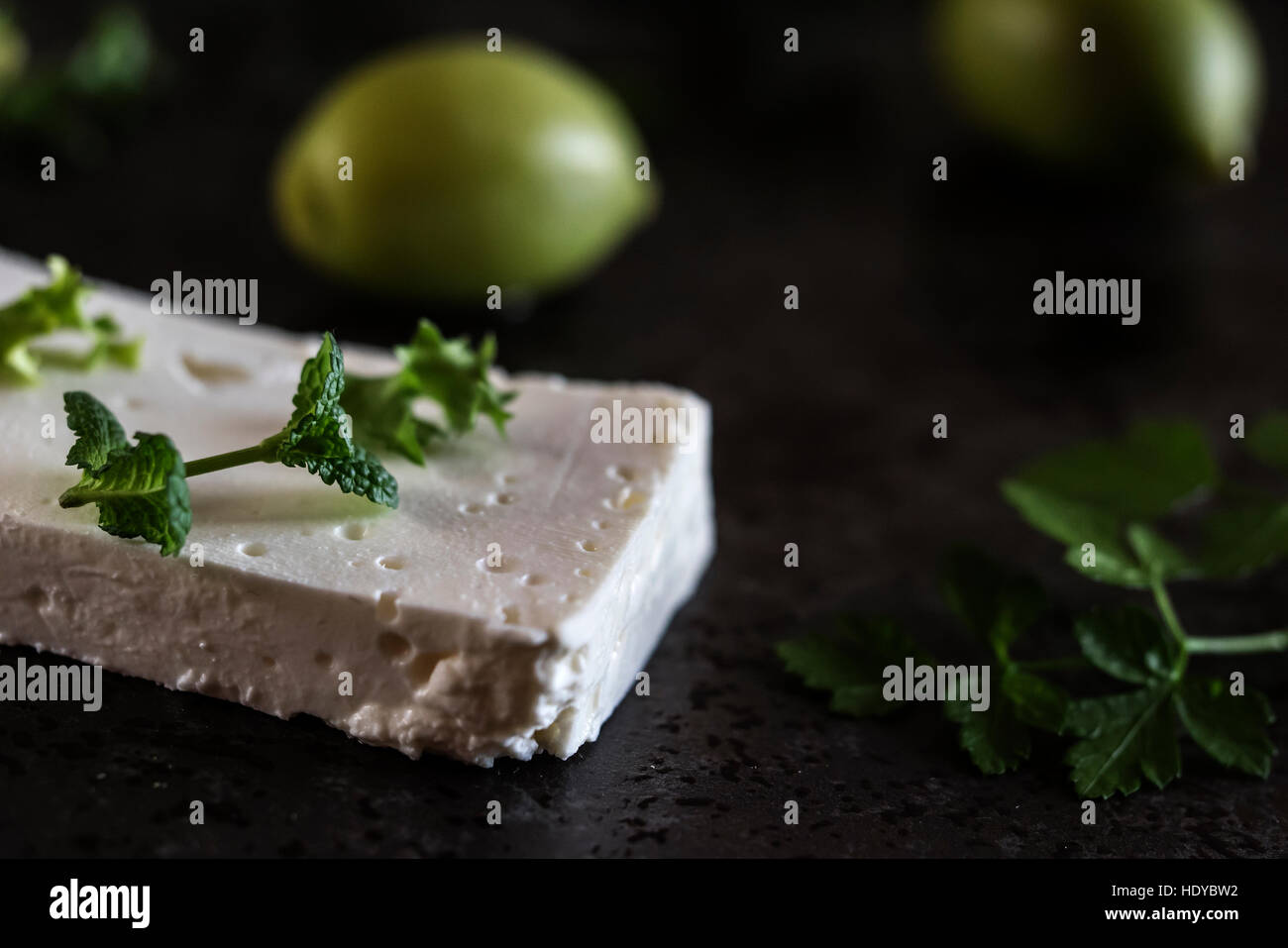 Le fromage Feta aux olives et d'herbes vertes sur fond de marbre gris. Selective focus Banque D'Images