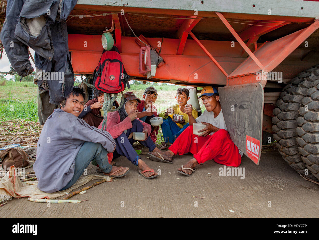 Champ de canne à sucre les ouvriers prennent une pause-déjeuner sous leur camion pour éviter la chaleur à Ma'ao, Negros occidental, aux Philippines. Banque D'Images