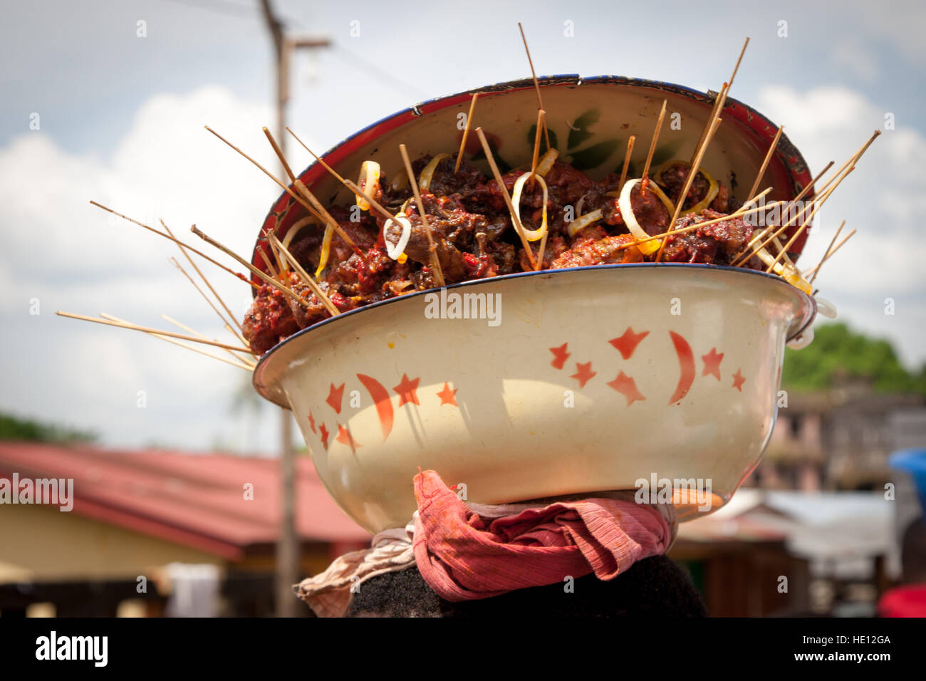 Un bol de brochettes de viande grillée est porté sur la tête en Sierra Leone. Banque D'Images