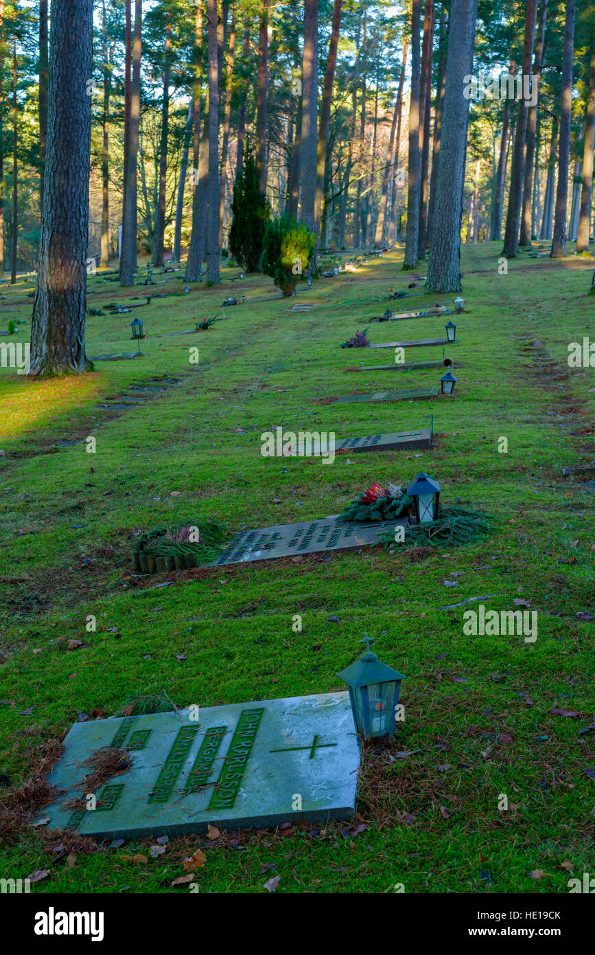 Bredakra, Suède - le 14 décembre 2016 : Documentaire de cimetière local. Pierres tombales ment, certains avec des lanternes, en milieu forestier. Banque D'Images
