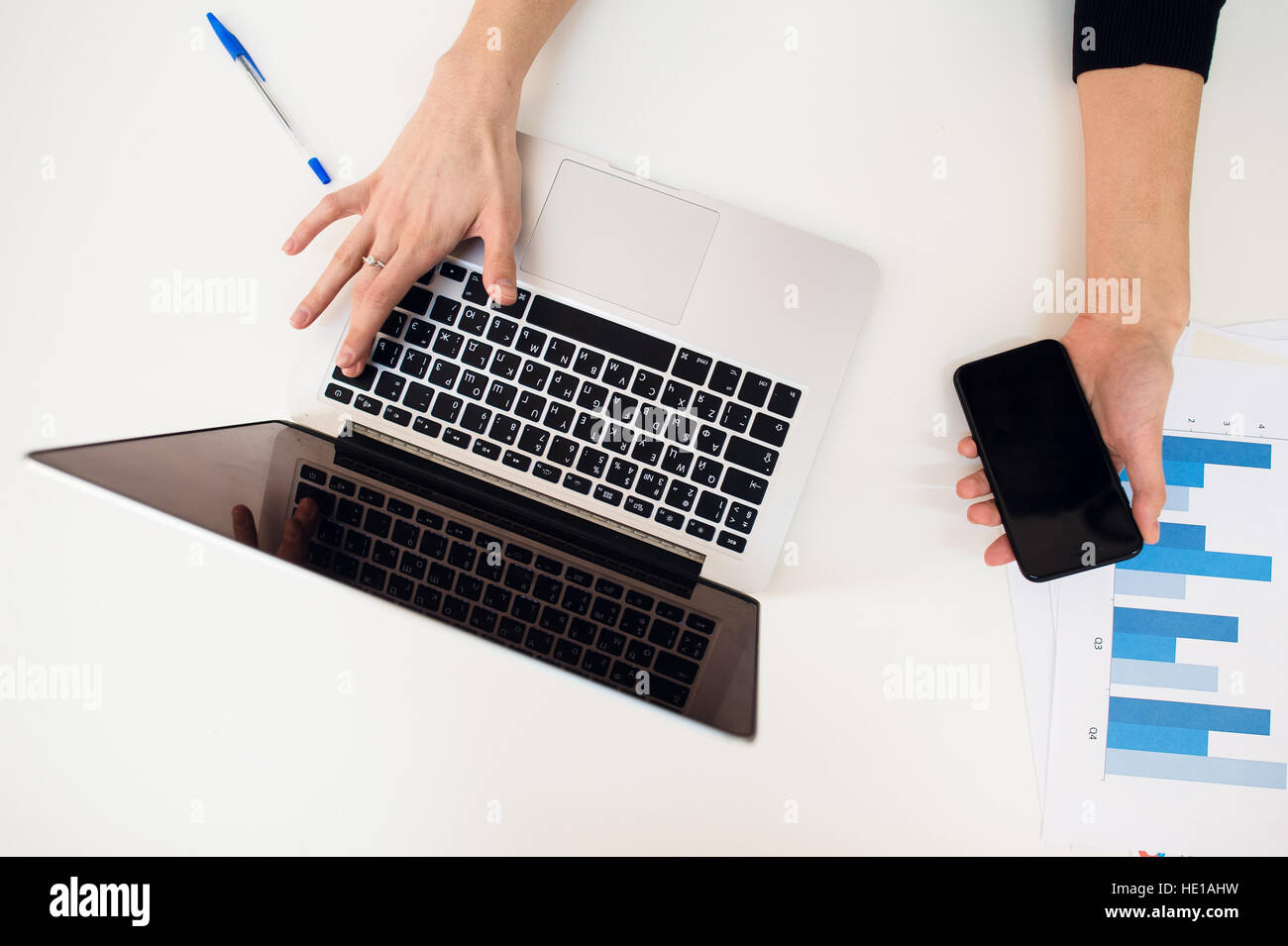 Ordinateur portable avec la main des femmes et du papier graphique sur le tableau blanc. Banque D'Images