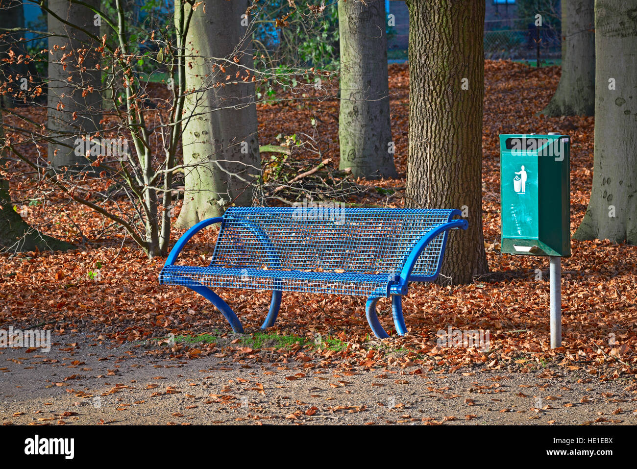 Banc de parc bleu vert avec une poubelle en automne Banque D'Images