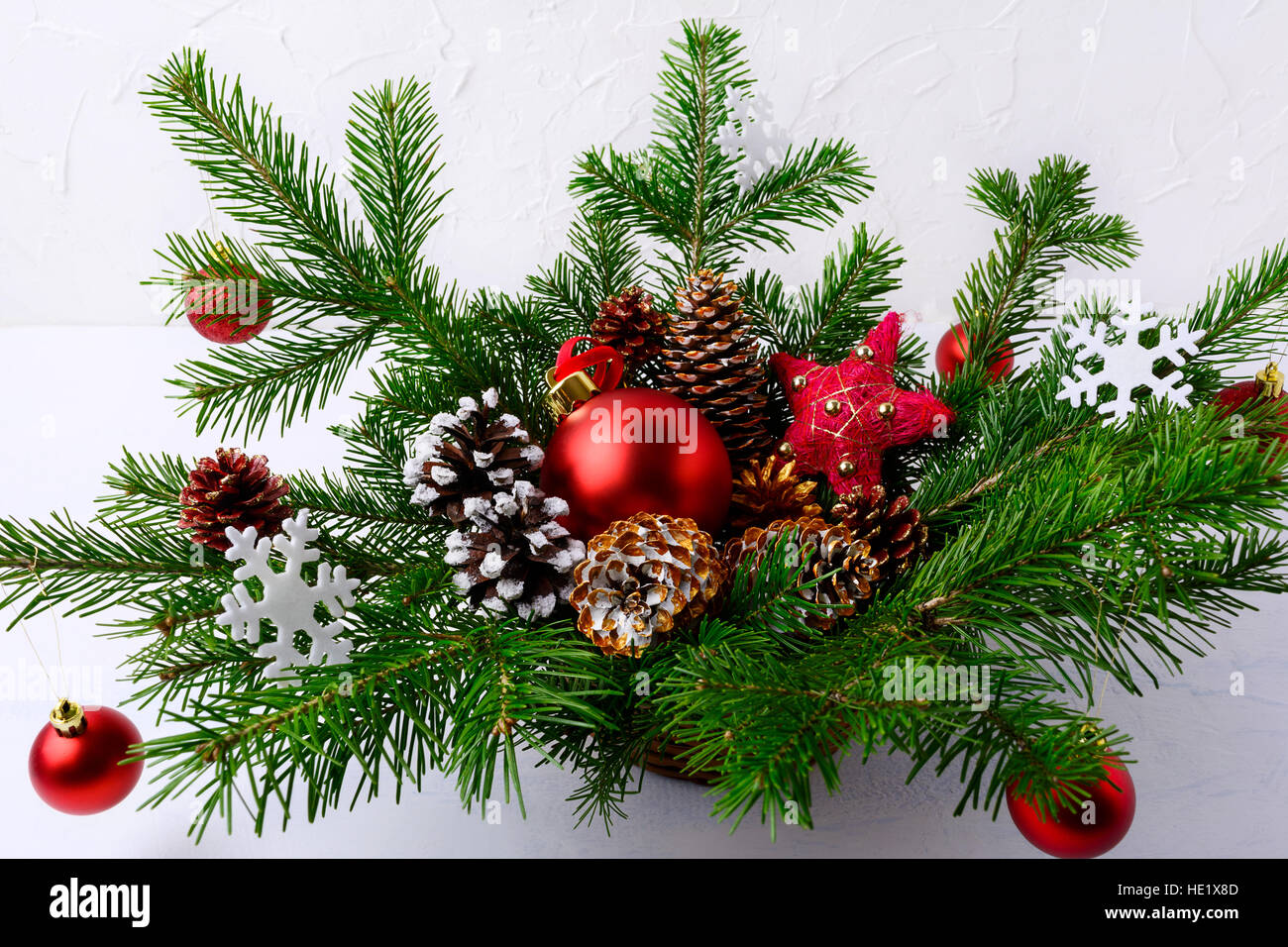 Centre de table de Noël avec des boules rouges et des pommes de pin  décorées à la main. Décoration de Noël avec des branches de sapin et boules  rouges. La verdure de