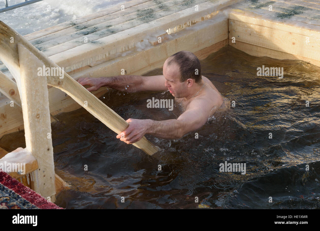 L'homme baigne dans l'eau froide de la glace-trou sur l'Epiphanie Jour. Une glace traditionnelle dans l'Eglise orthodoxe Saint Jour de l'épiphanie Banque D'Images