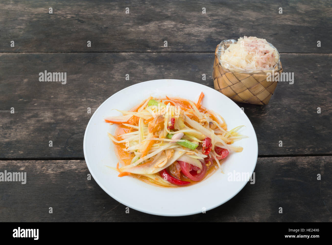 Som tam, salade de papaye verte ou thaïlandais avec riz gluant dans le bambou conteneur sur table en bois au restaurant. Banque D'Images