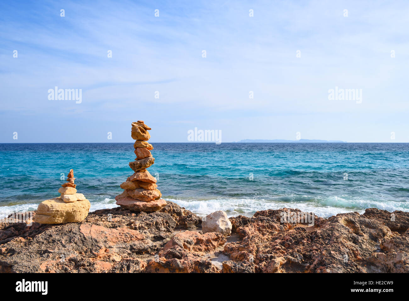 Pyramide en pierre sur la côte rocheuse d'une mer ondulée bleu Banque D'Images