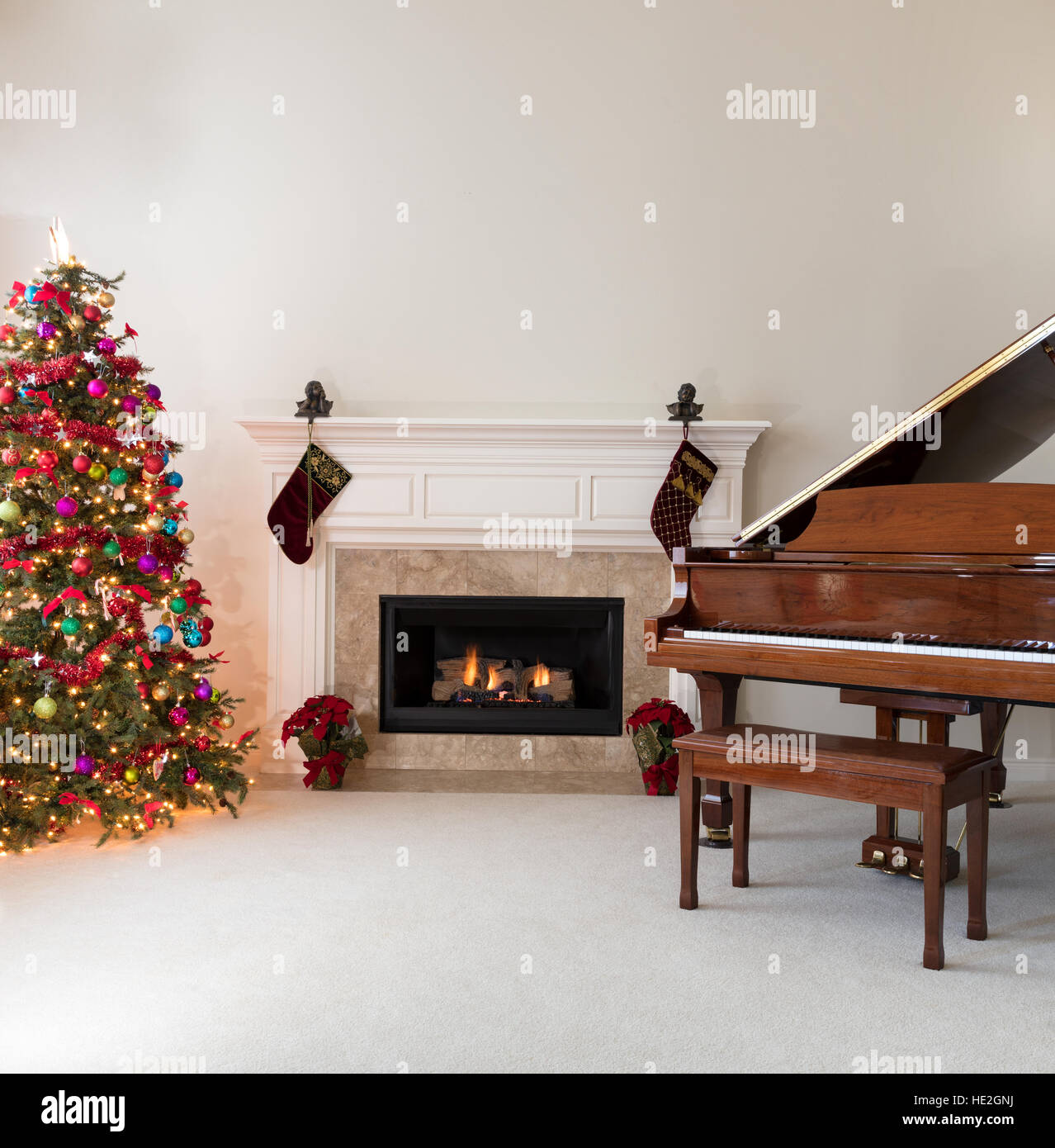 Salle de séjour avec cheminée rougeoyante, piano à queue et l'arbre de Noël décoré pour les fêtes Banque D'Images