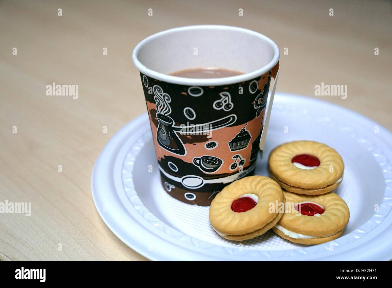 Tasse de café en papier et de sandwich cookies avec de la confiture de fraise dans la plaque en plastique sur la table en bois Banque D'Images