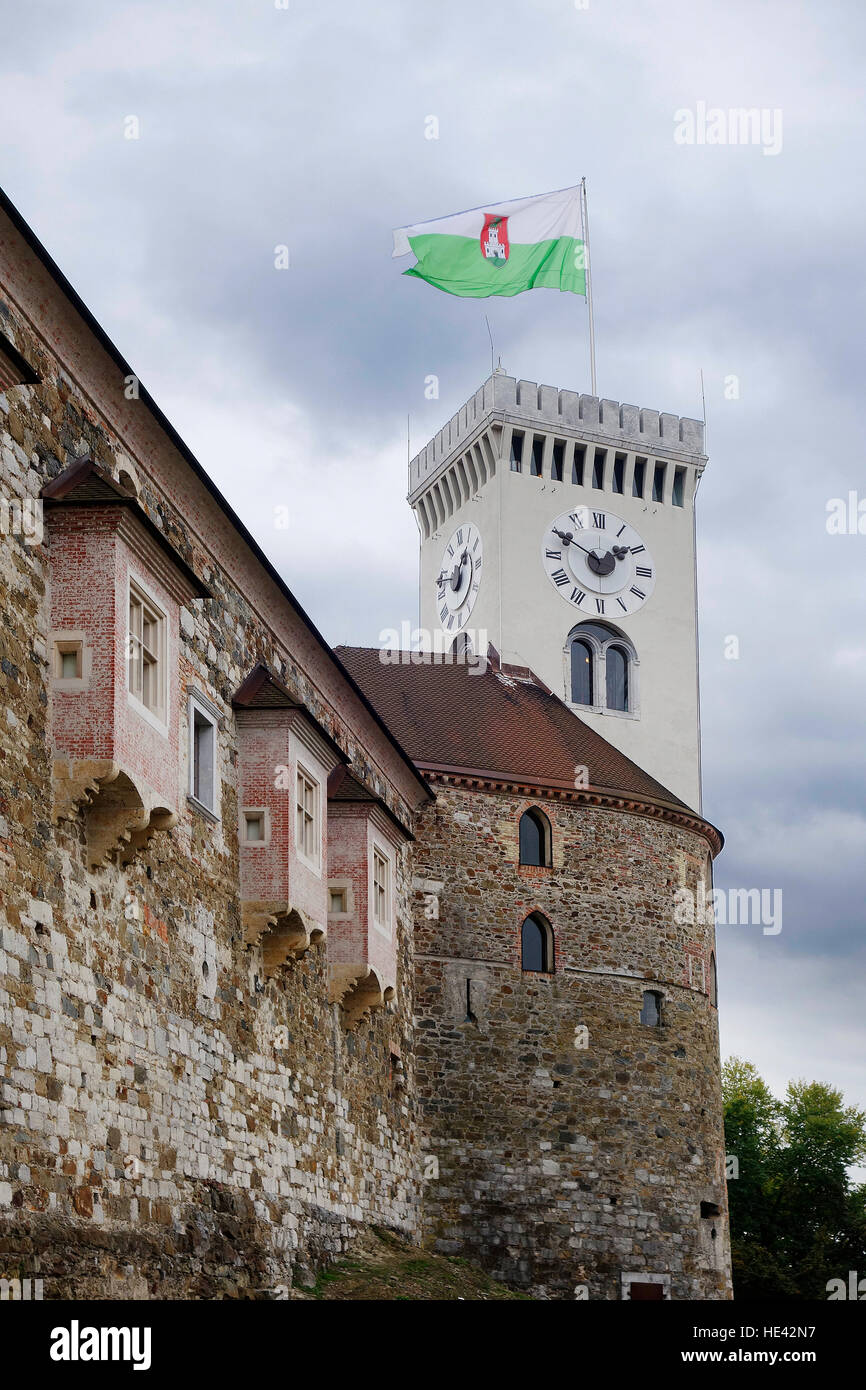 Vue sur la partie du mur ouest, le château de Ljubljana avec tour de ville et drapeau. Banque D'Images