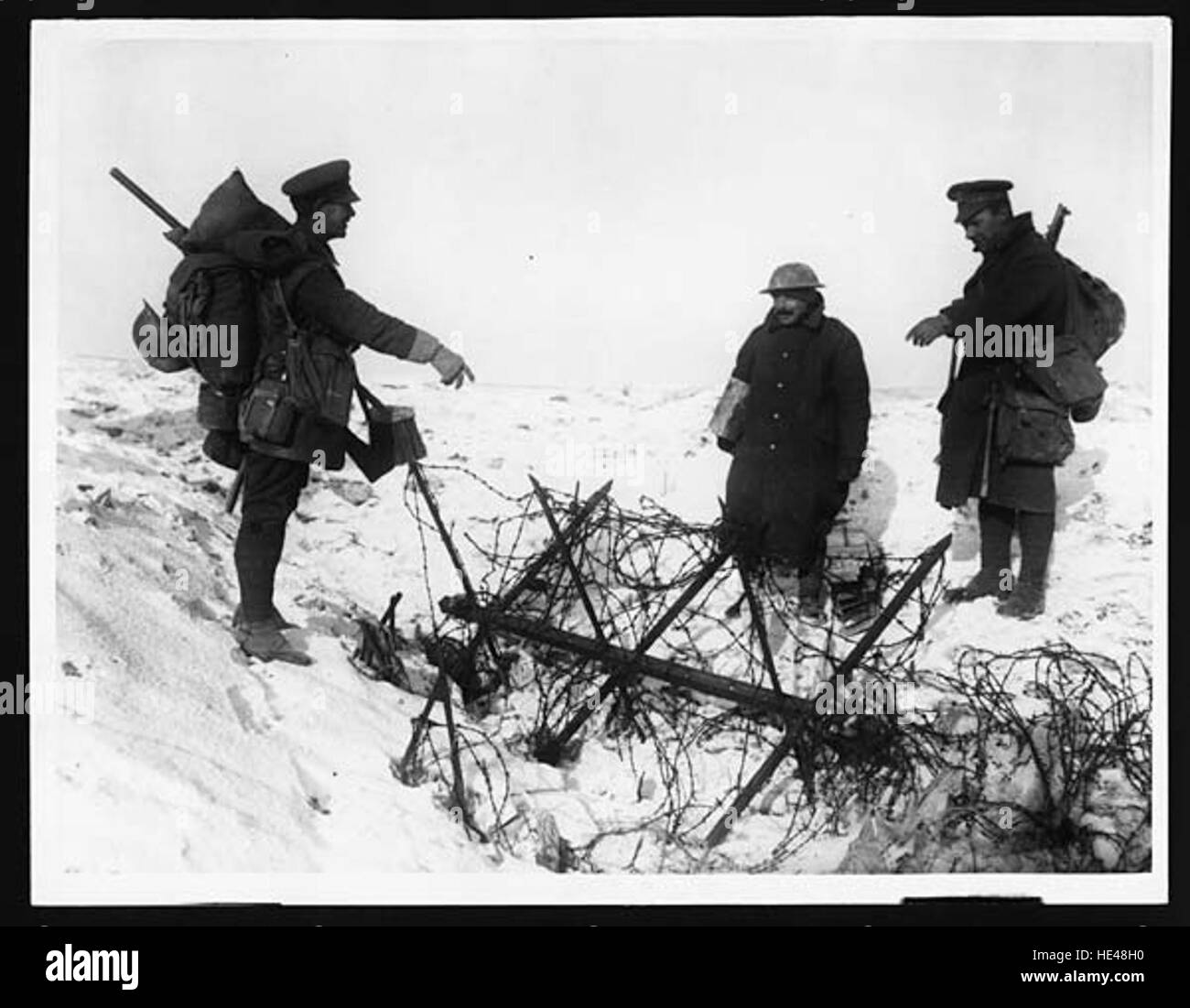 Cette image représente un homme réfléchissant sur un lieu marqué par des barbelés, évoquant des souvenirs de difficultés et de conflits passés. L'image sert de rappel poignant des luttes historiques et de l'impact de la guerre. Banque D'Images