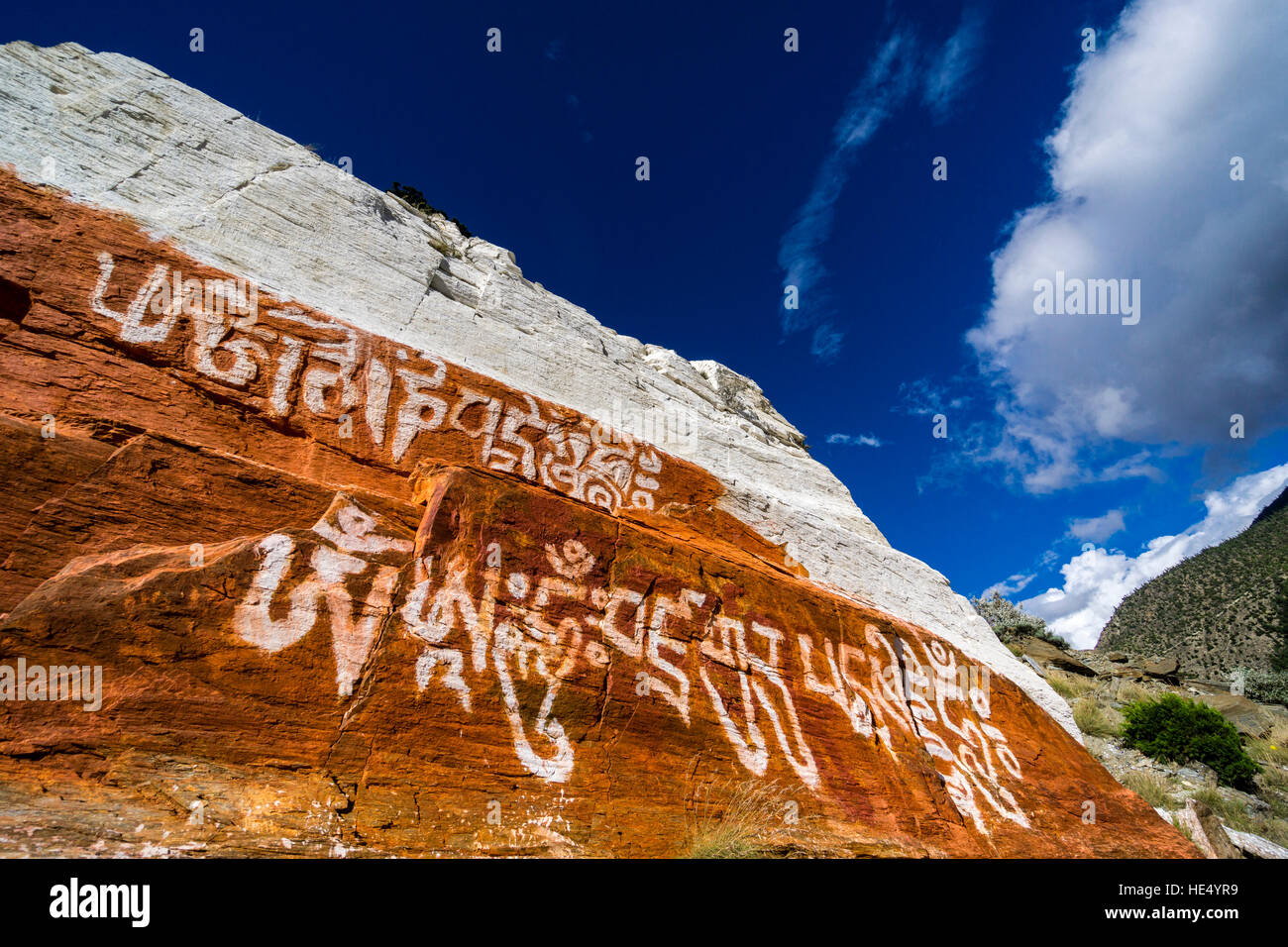 Un rocher au-dessus du village est peint en rouge et blanc avec quelques écritures tibétain pour des raisons religieuses Banque D'Images
