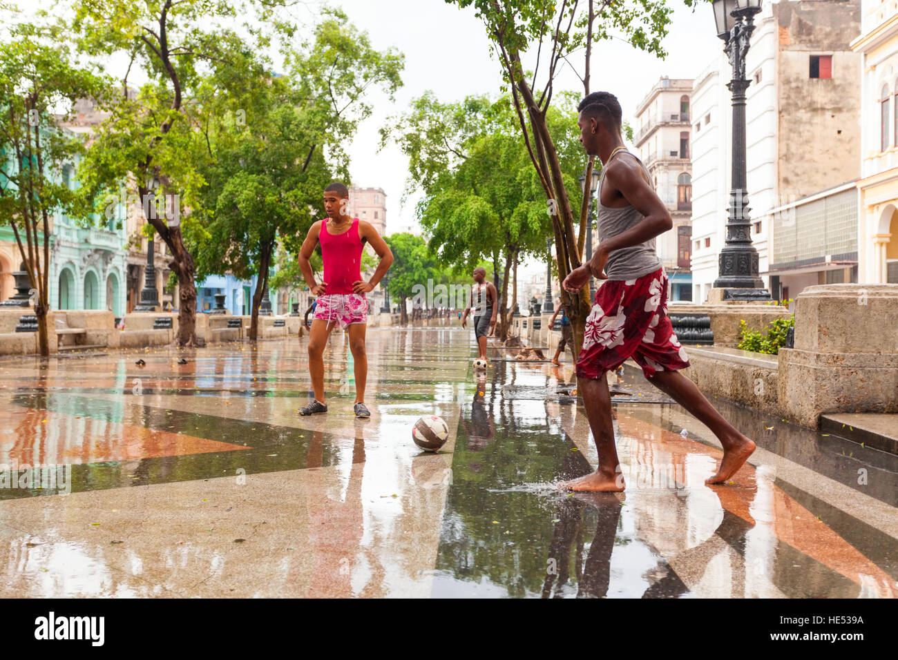 Les adolescents jouent au soccer (football) dans la pluie le long de Paseo de Marti dans la Vieille Havane, Cuba. Banque D'Images