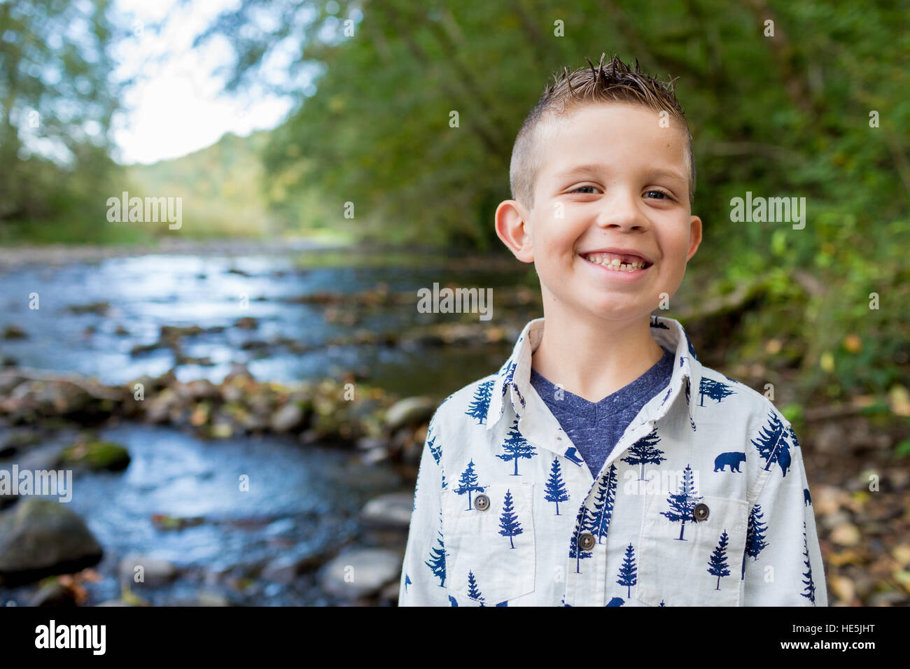 Jeune garçon posant pour un portrait de vie en plein air le long des rives de la rivière McKenzie dans l'Oregon. Banque D'Images
