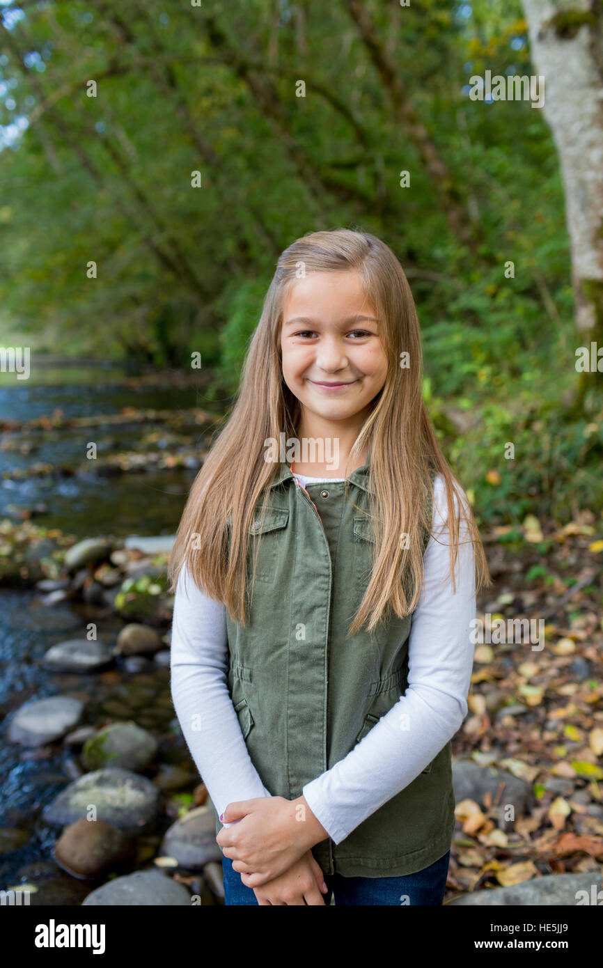 Jeune fille dans un gilet vert posant pour un portrait de vie en plein air le long des rives de la rivière McKenzie dans l'Oregon. Banque D'Images