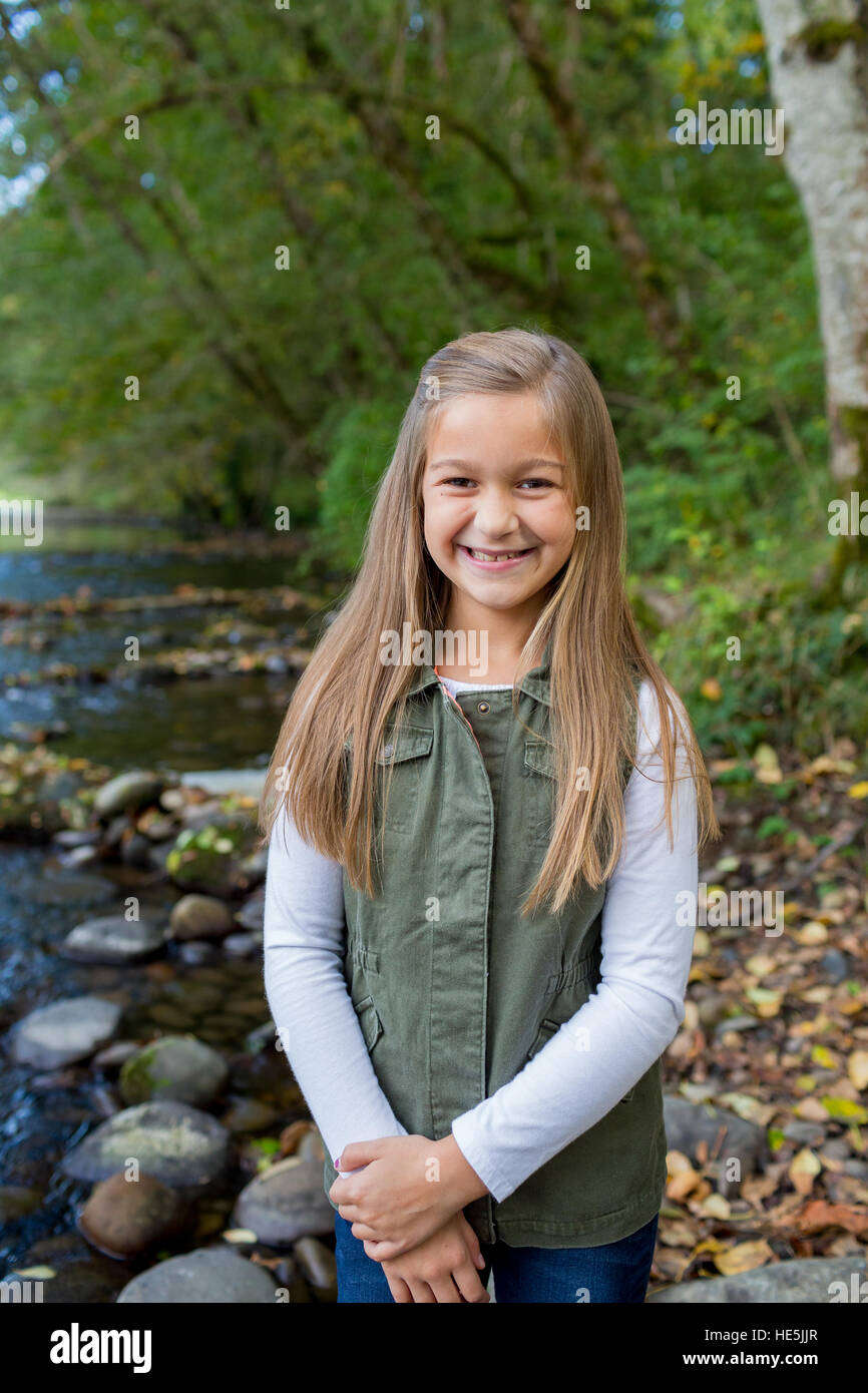 Jeune fille dans un gilet vert posant pour un portrait de vie en plein air le long des rives de la rivière McKenzie dans l'Oregon. Banque D'Images